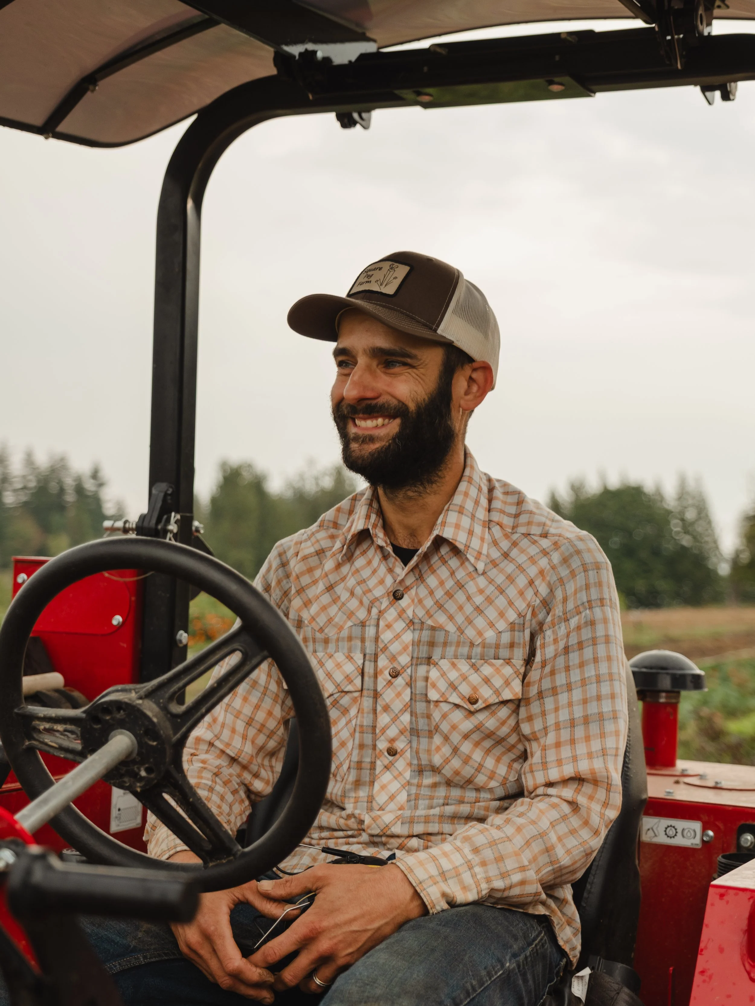 farmer smiling sitting on red tractor.