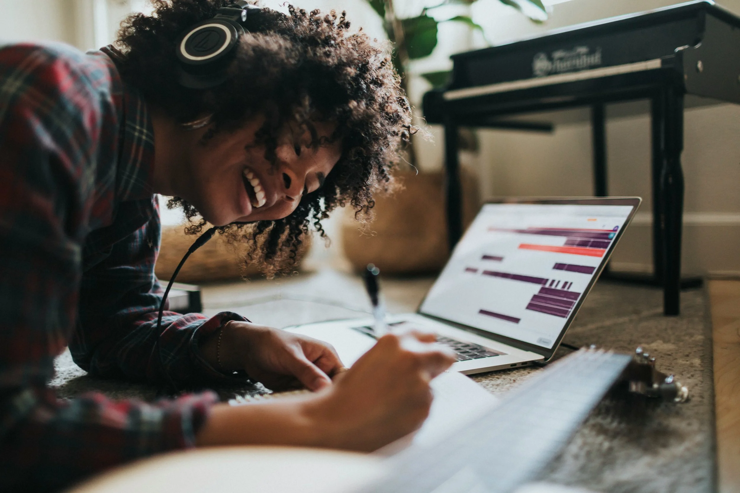 Black Woman smiling and writing with headphones on after virtual therapy for women in Chicago