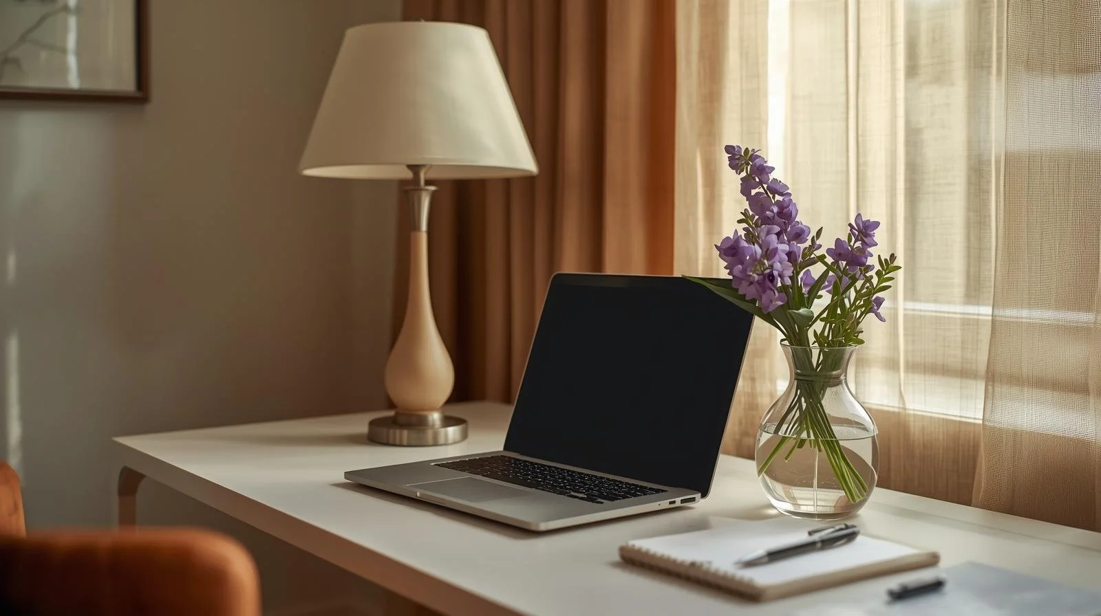 Laptop, notebook with pen, and flowers on a desk in a bright, calming workspace for online therapy in Chicago and Illinois.