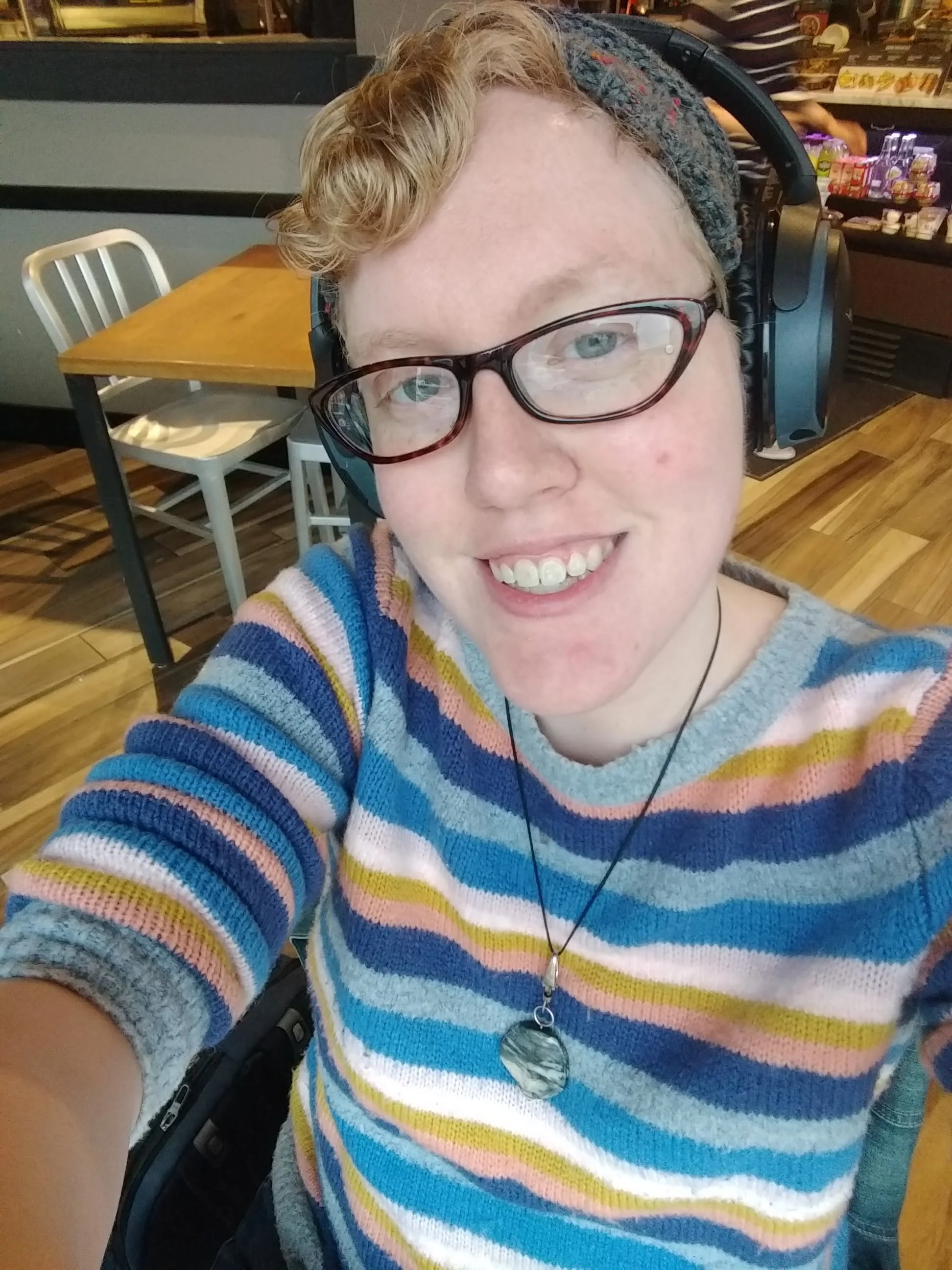 Therin, a trans-affirming therapist, wearing headphones in a coffee shop, providing online therapy in Chicago and Illinois.