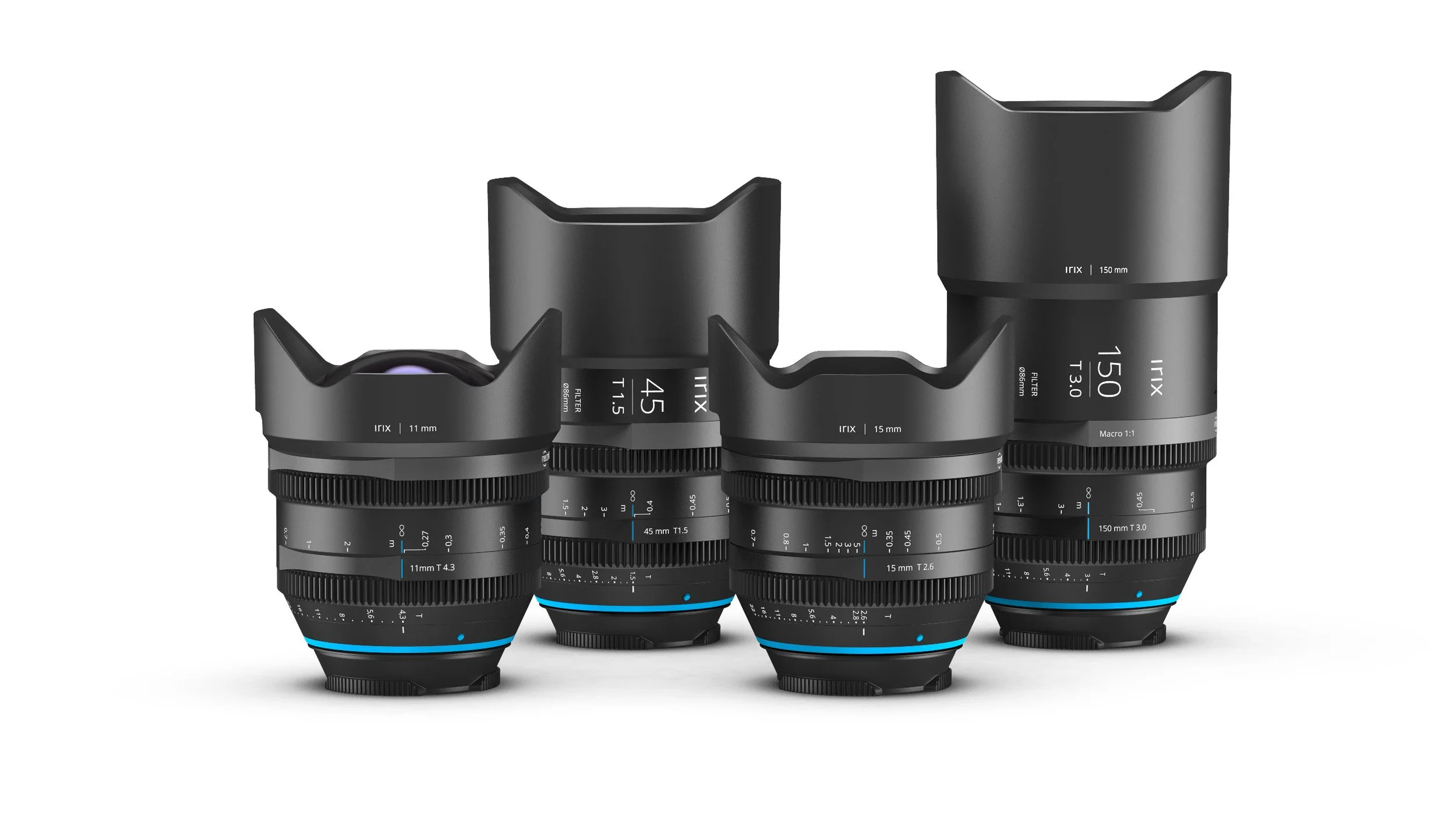Four camera lenses of different sizes and focal lengths lined up on a white surface.