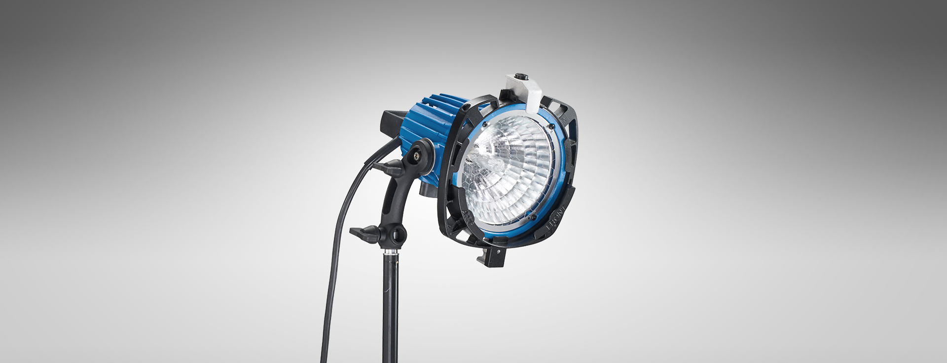 Studio light with blue and black housing and a reflector, mounted on a stand, isolated on a gray background.