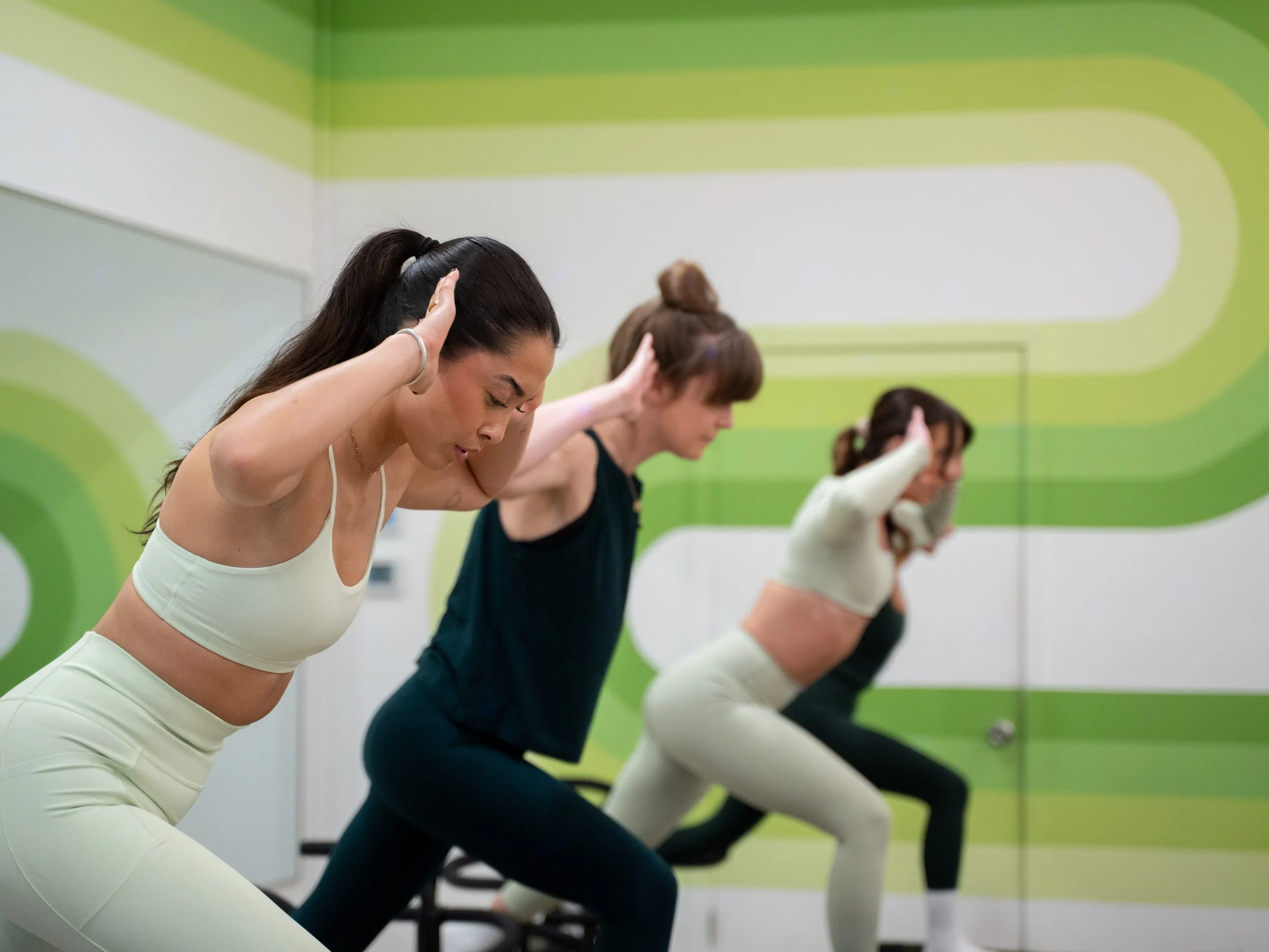 Four women in workout attire doing pilates, yoga, lagree in a Boulder Colorado's grooviest fitness studio, Lagroove - a fully Lagree Certified workout studio.