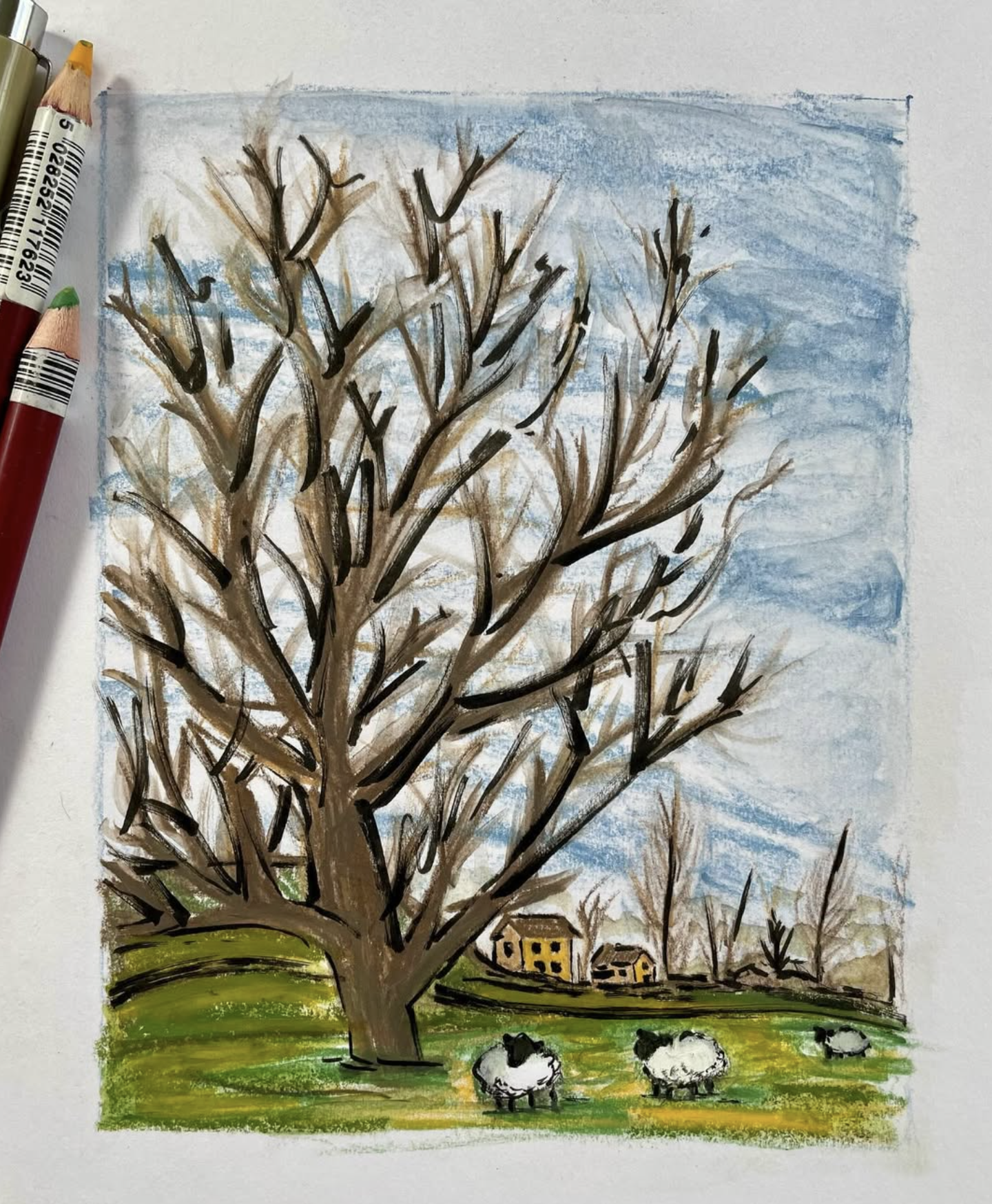 Child's drawing of a large winter tree with leafless branches, green grass, three sheep, and a small village with houses in the background, under a blue sky.