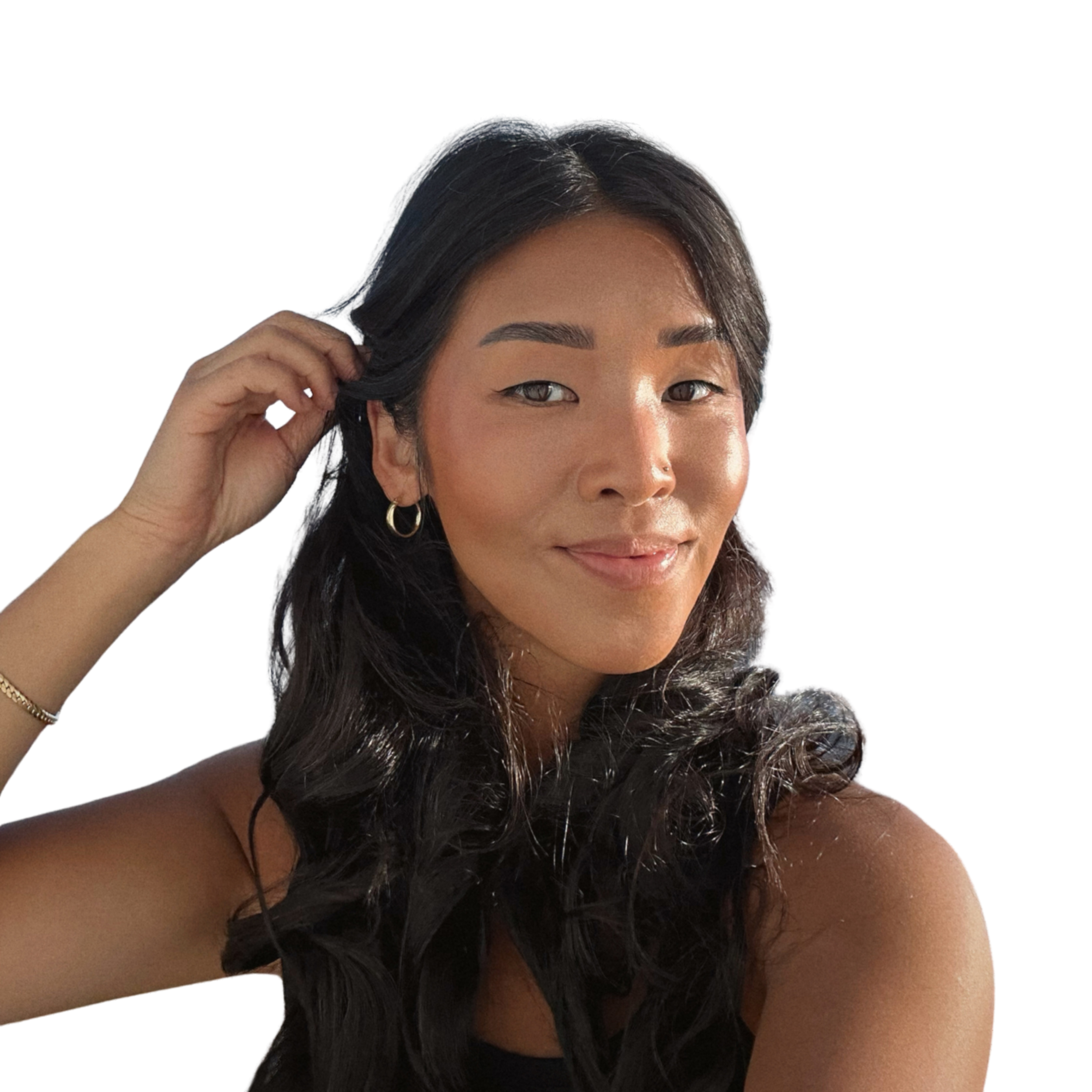 A woman with long dark hair and gold hoop earrings, smiling, wearing a white crochet top and black shirt against a white background.
