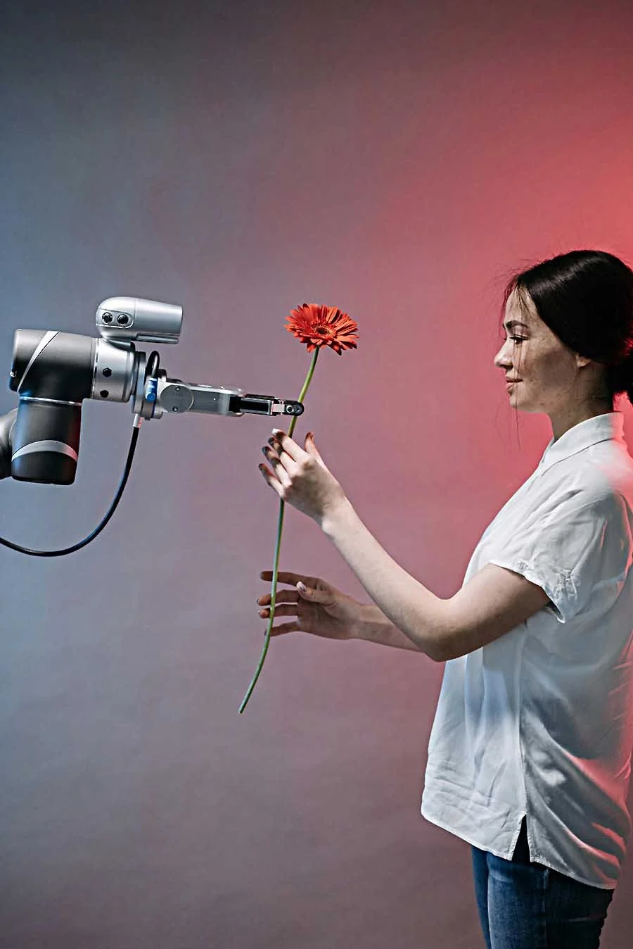 Woman reaching for a flower that is being handed to her by a robotic arm