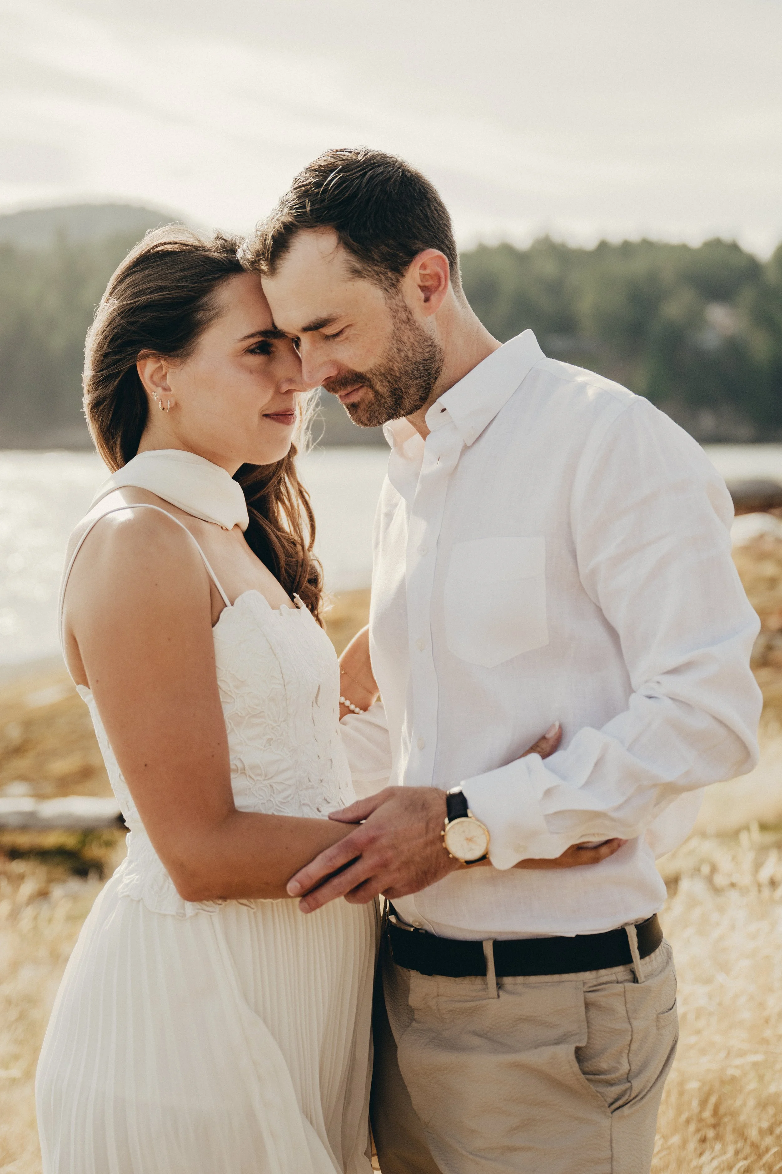 Bride and groom on Galiano Island, in a golden field near the sea