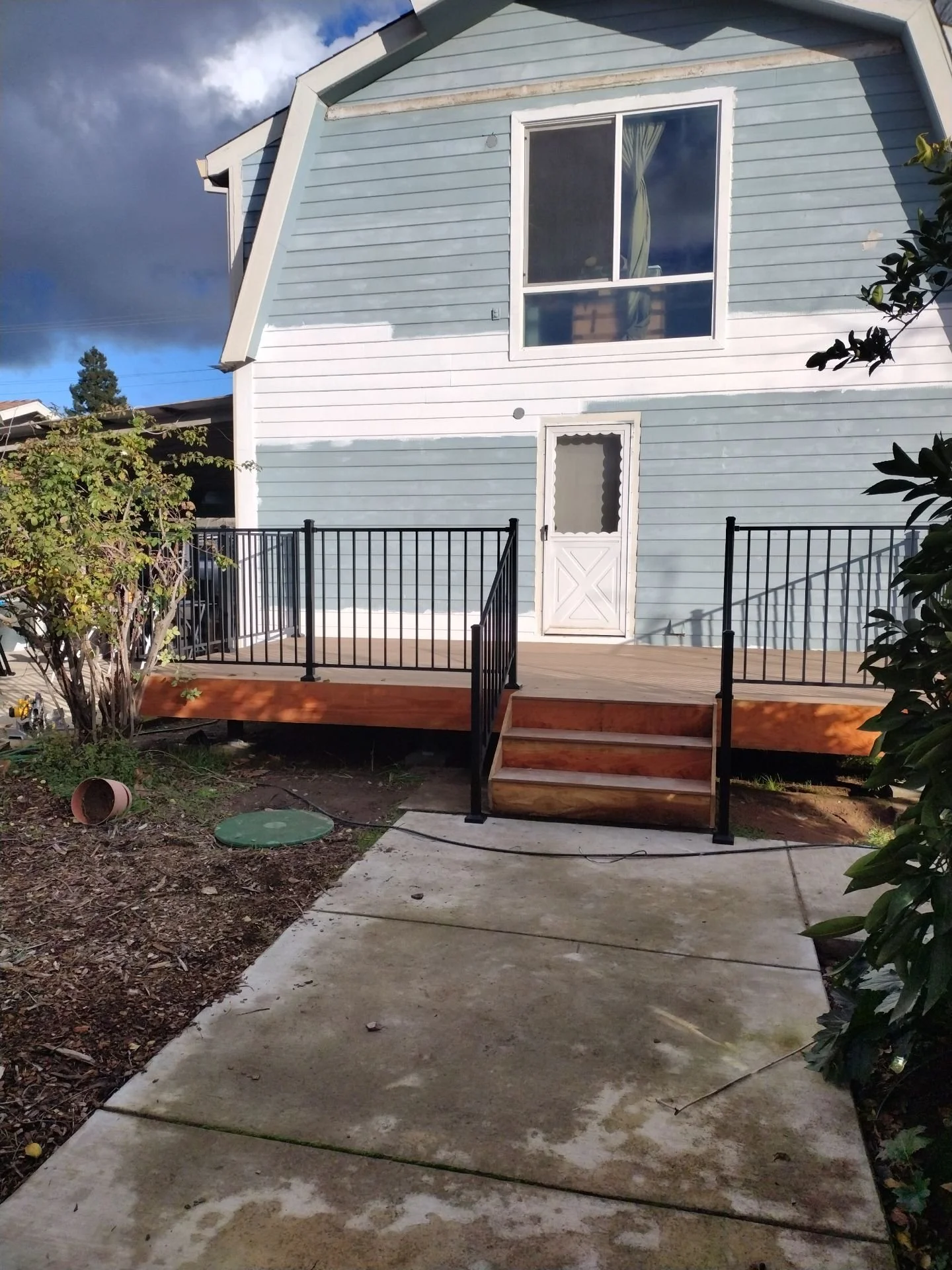New deck with black metal railings and steps, with siding primed for paint, in Rio Linda
