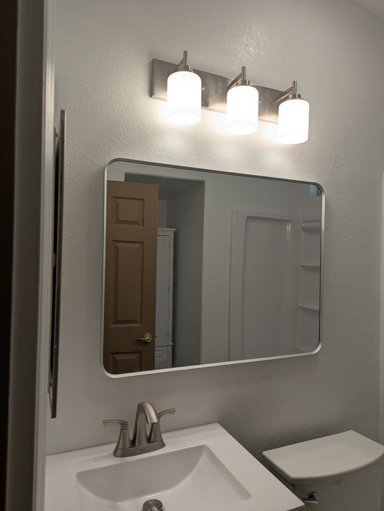 New mirror and three-light fixture over the sink in a remodeled Rio Linda bathroom