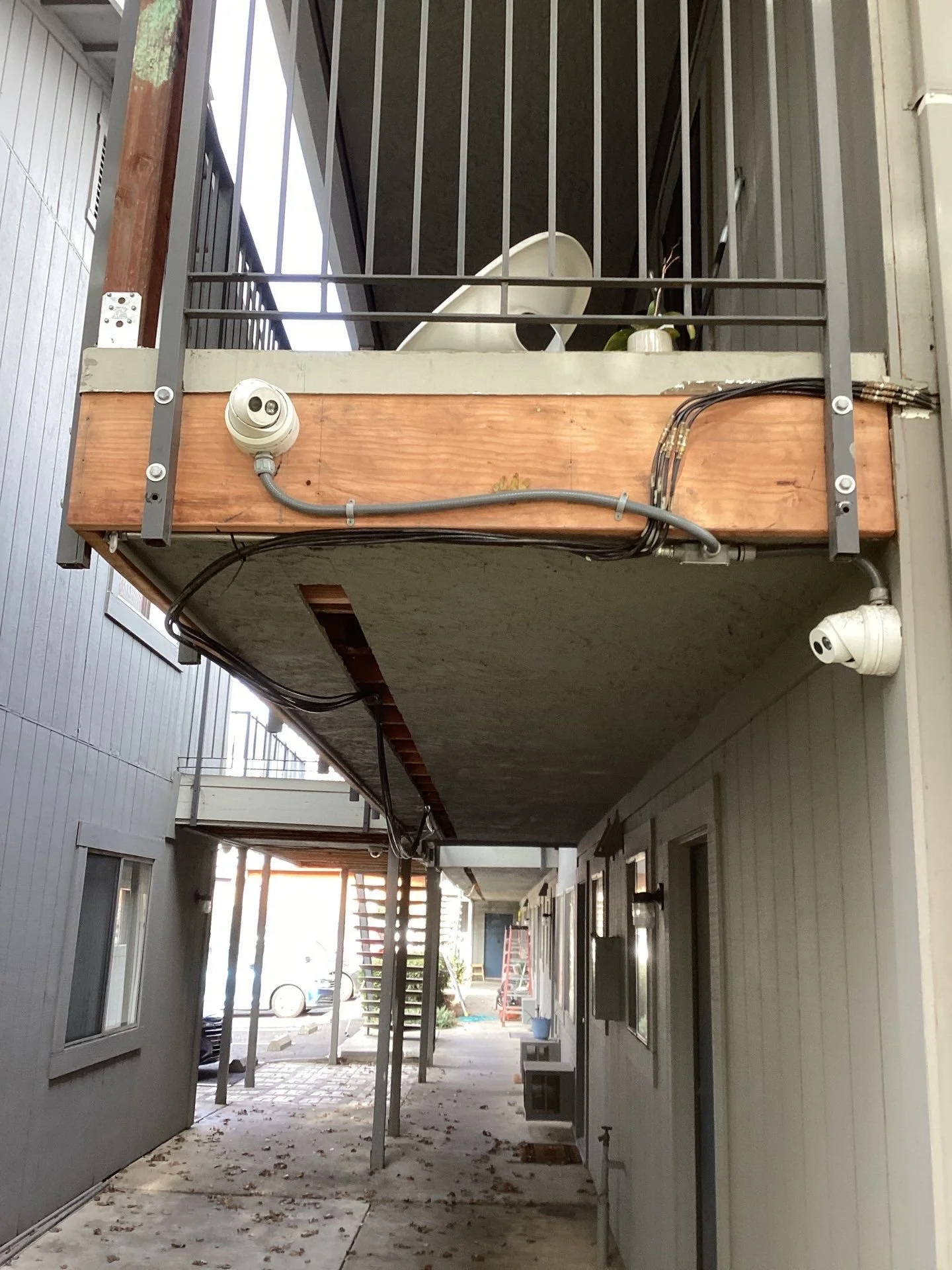 Damaged rim beam under a second-story apartment walkway in Sacramento before repairs