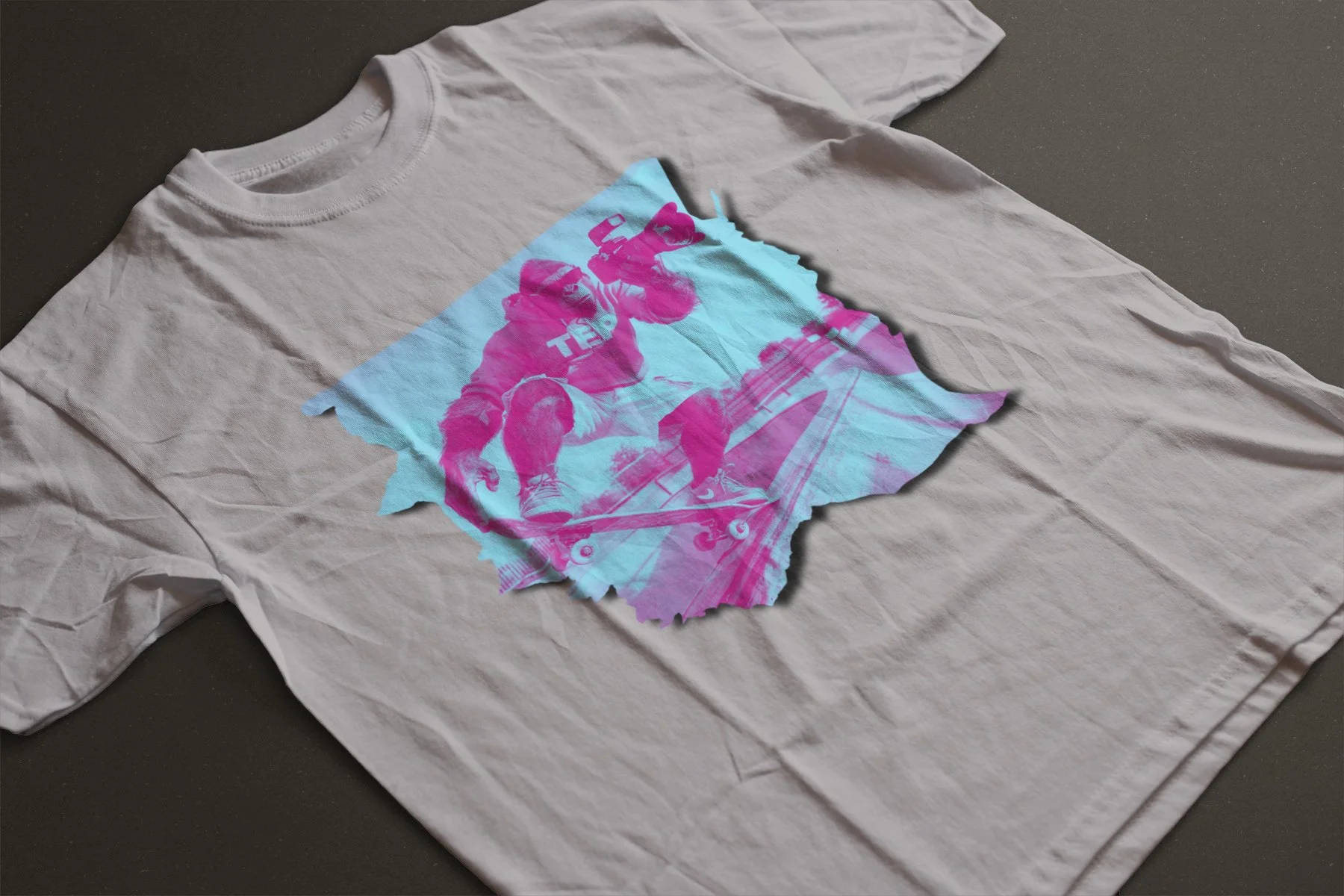 Flat lay of a white 100% cotton TEP Nosegrab Tee featuring a pink and cyan vaporwave graphic of a skateboarder performing a nosegrab on a ramp, relaxed fit skate apparel.