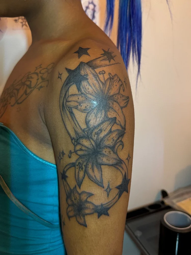 Lilies and stars tattoo on the upper arm and shoulder by Summer