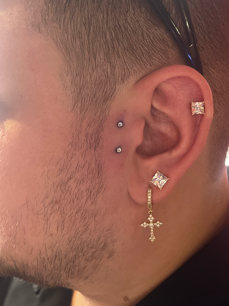 Ear piercings with premium jewelry at Red Ink Tattoo Studio