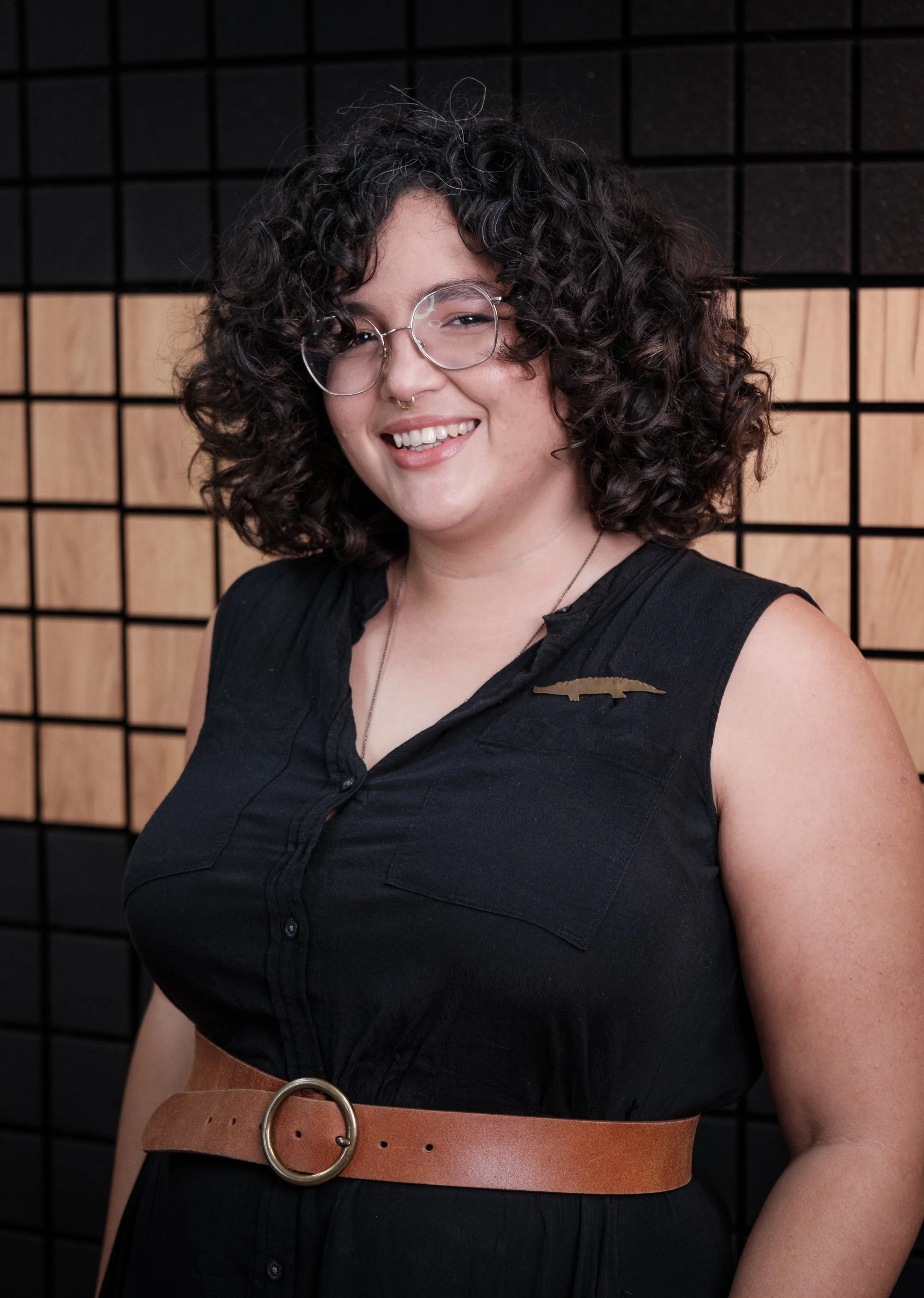 Adriana García, augmented reality designer and Command Z collaborator from Puerto Rico, wearing a black dress and large eyeglasses. She looks confidently at the camera, reflecting her innovative and creative expertise.