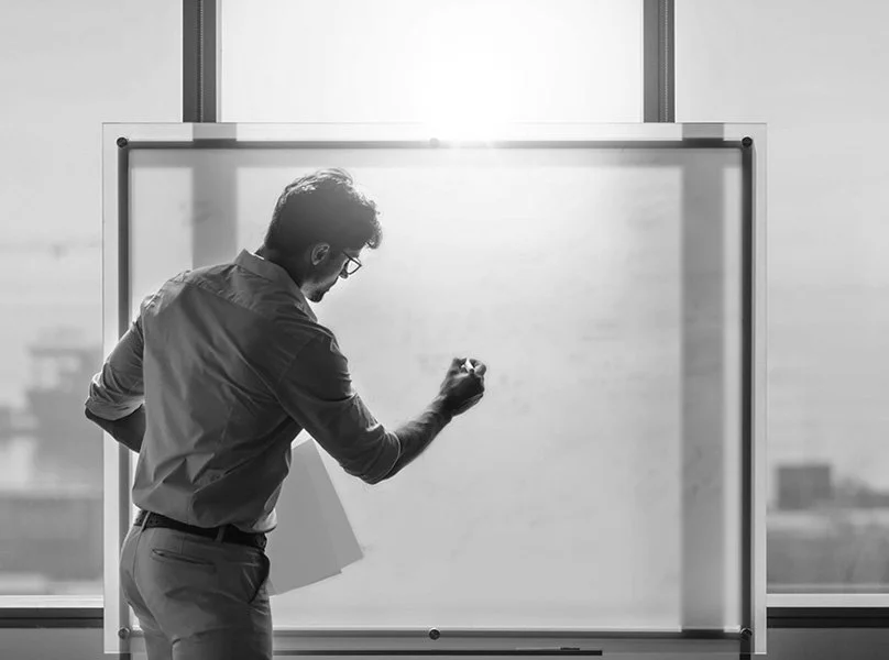 Marketing professional strategically writing on whiteboard to illustrate the process of our Brand Auditing service