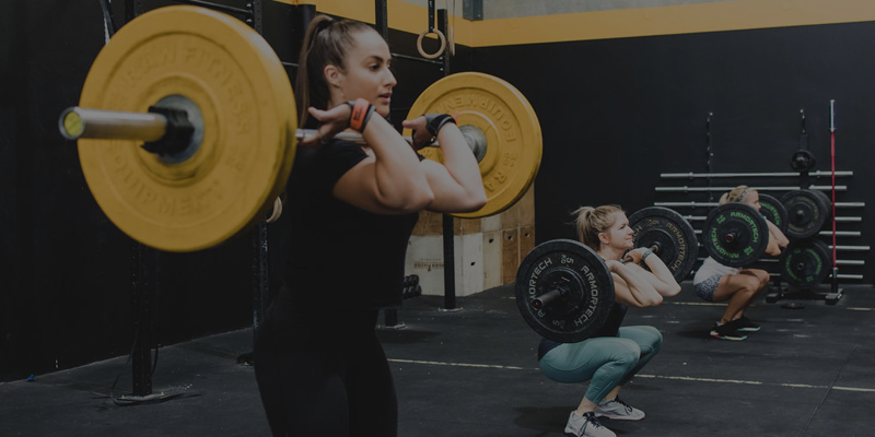 Women lifting barbells during a workout session at a gym
