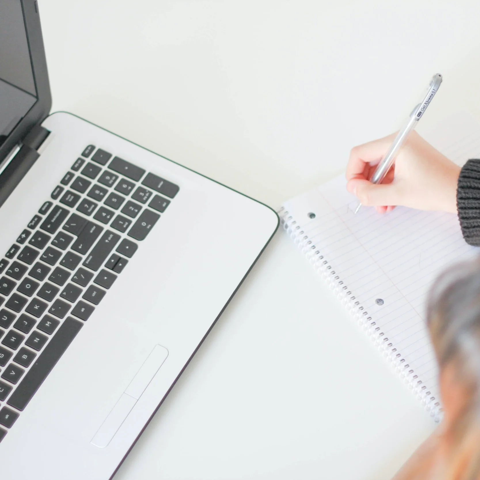eCommerce shop owner checking Pinterest marketing results on her laptop and writing in her notebook