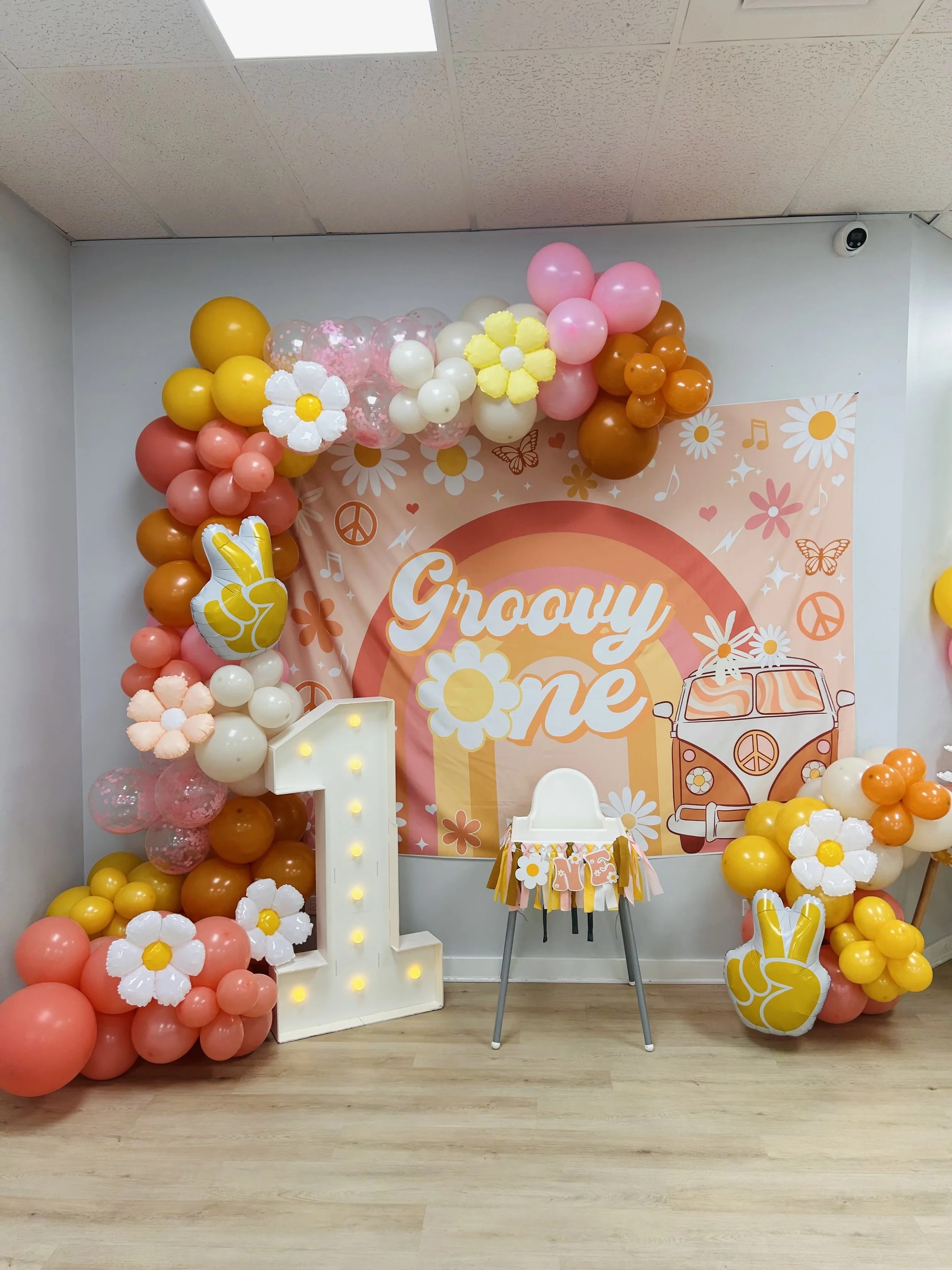 first birthday party decor. a one year olds first birthday backdrop "groovy one" with a colorful balloon arch and a decorated highchair. babys first birthday party. birthday party for kids. 
