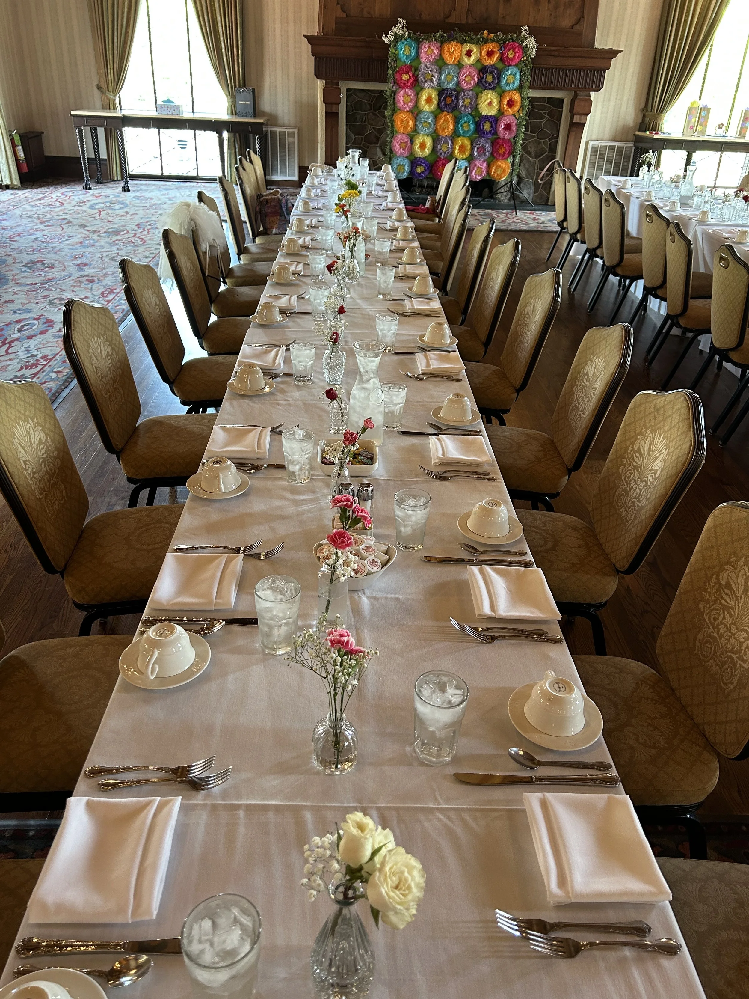 long table with florals in bud vases to decorate a table. multi colored florals to make the event fun and bright. a beautiful tablescape for a bridal shower. 