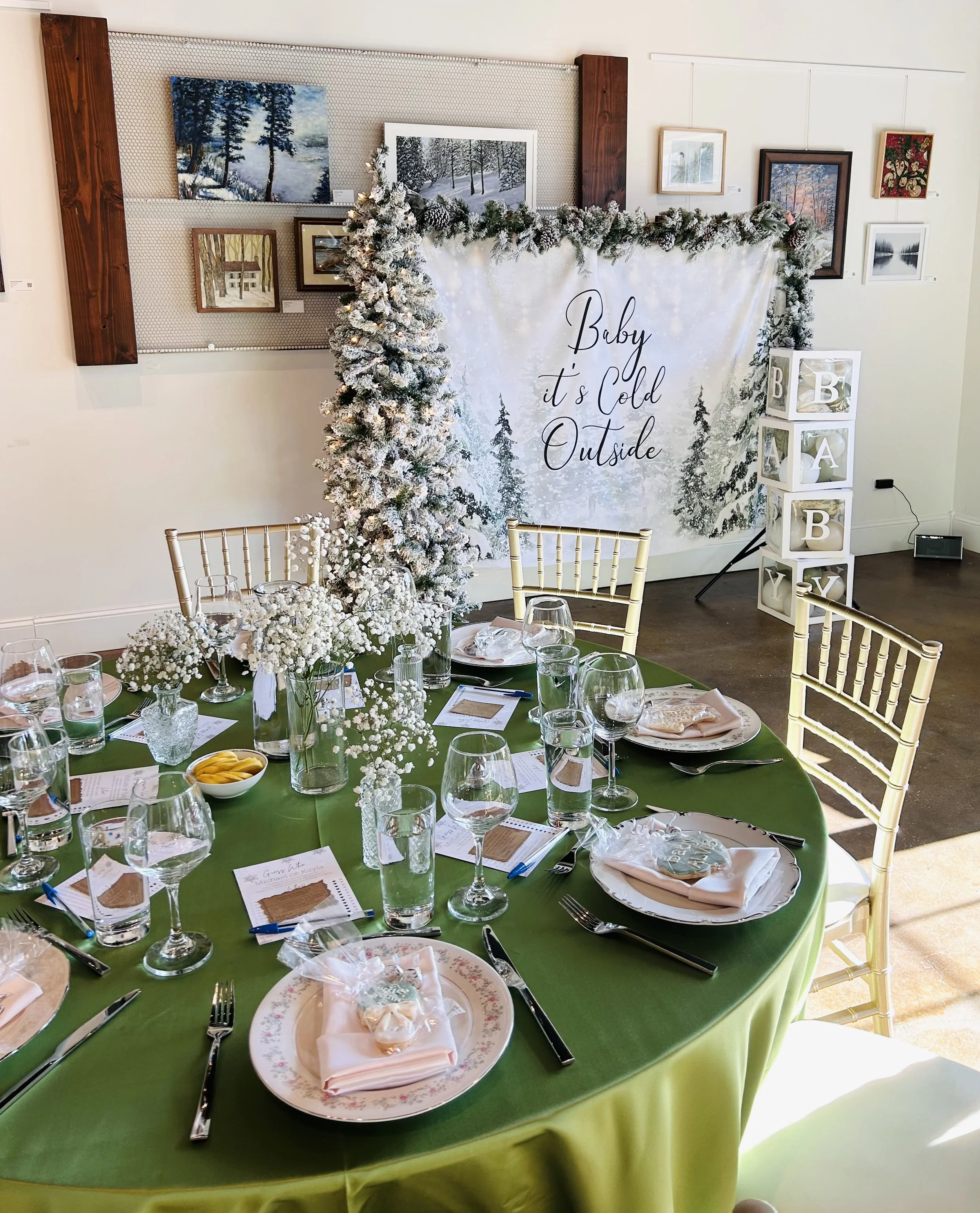 baby its cold outside baby shower set up. green table cloths with babys breath centerpieces. amazing winter themed backdrop with garland and balloons in boxes that read baby. perfect set up for adorable baby shower. 