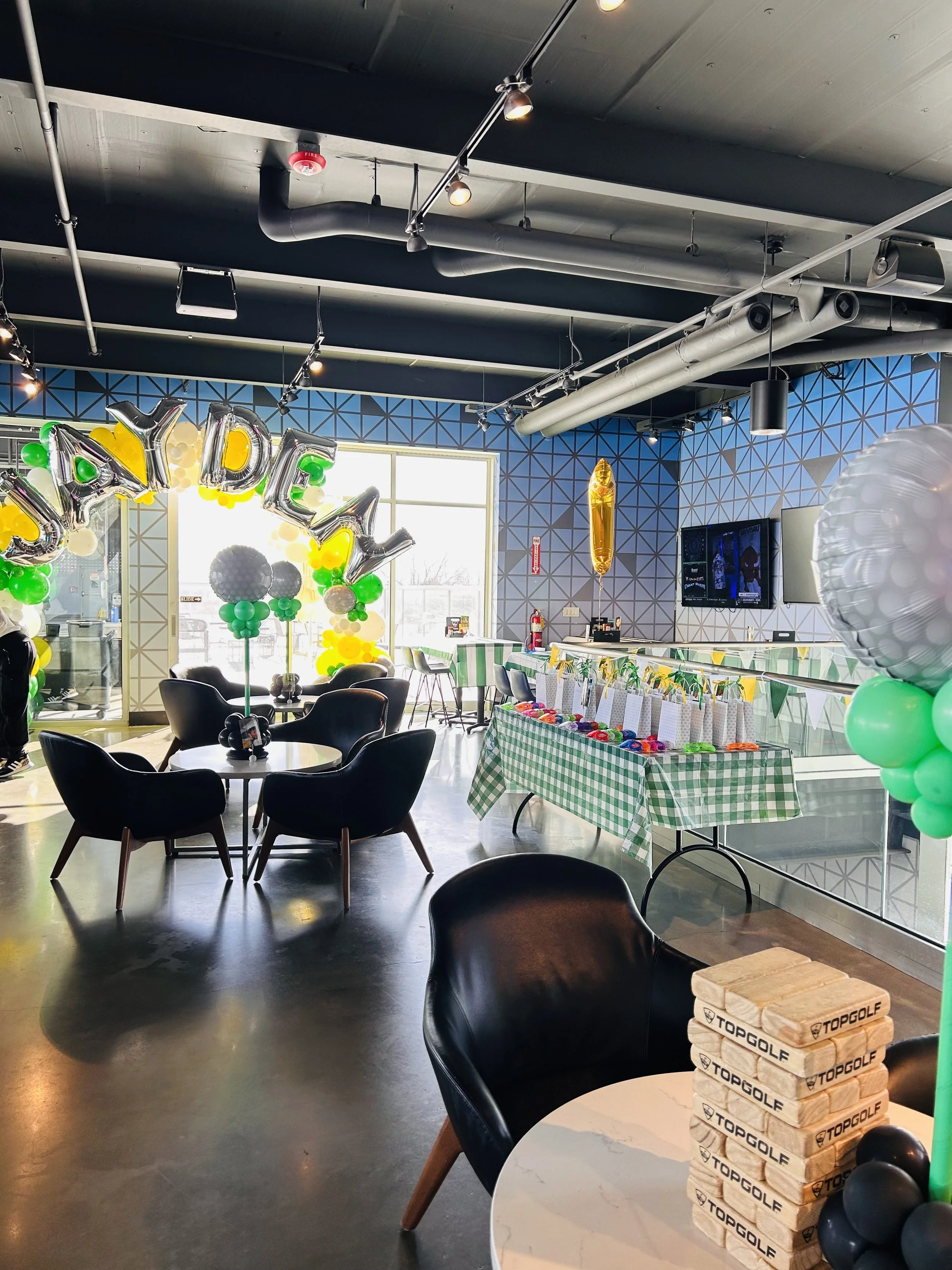 full view of a kids golf themed birthday party. huge 10ft balloon arch with themed colors and birthday boys name on the balloon arch. golf ball balloons and fun games. 