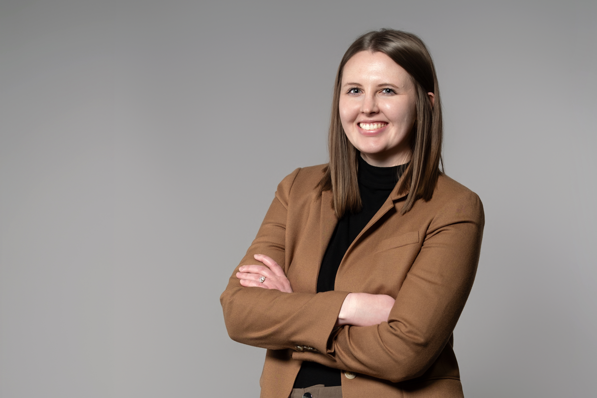 Brandy Foust, promoted at encompas from Account Manager to Design Director in 2026. White woman with light brown straight hair standing with arms crossed, smiling and wearing a black turtleneck with a brown blazer.