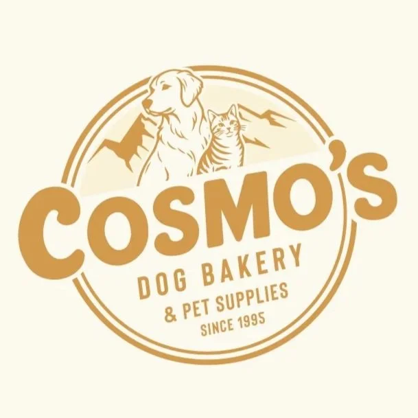 Logo for Cosmos Dog Bakery & Pet Supplies featuring a dog and a cat with mountains in the background, established in 1995.