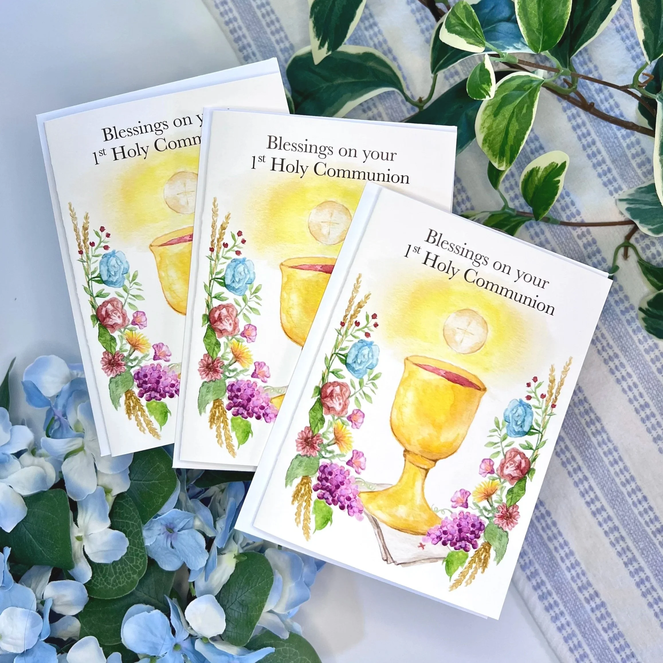 Multiple watercolor 1st Holy Communion card that say, "Blessings on your 1st Holy Communion" on the front