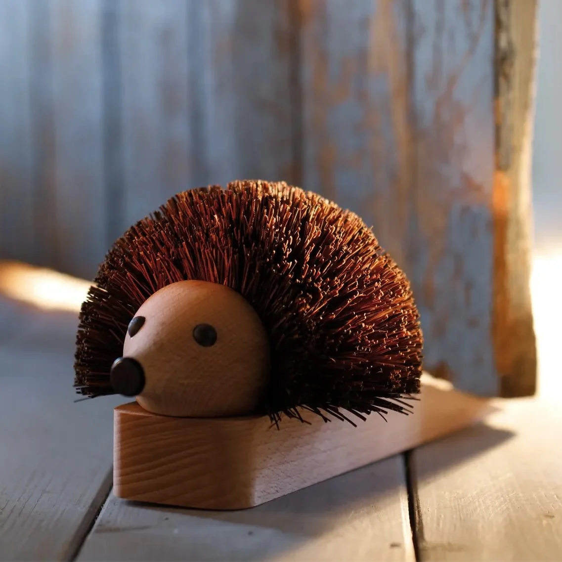 Wooden hedgehog figurine with a rounded body, small face, and bristly back, placed on a wooden surface.