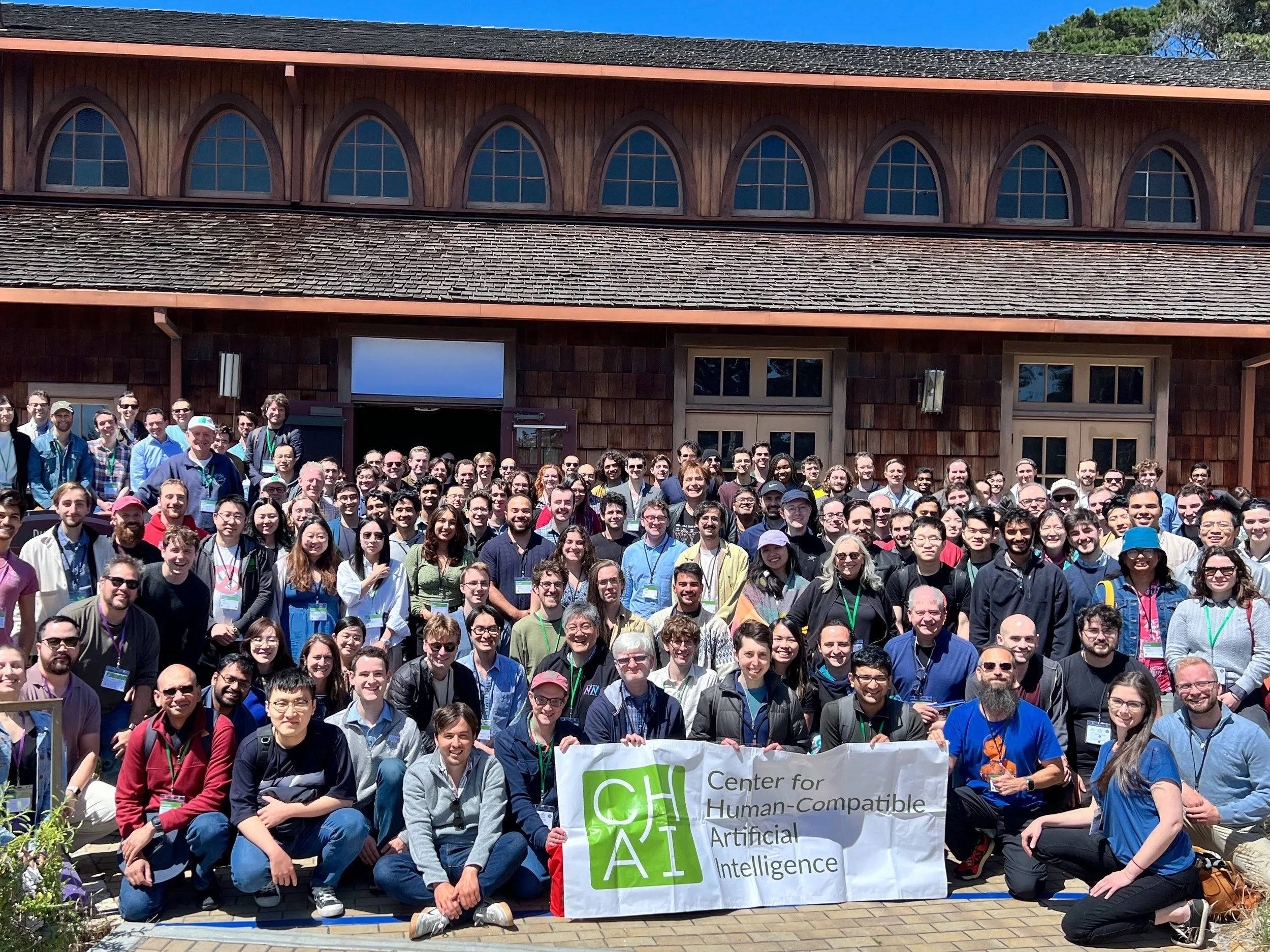 Conference attendees outside a building holding a CHAI banner