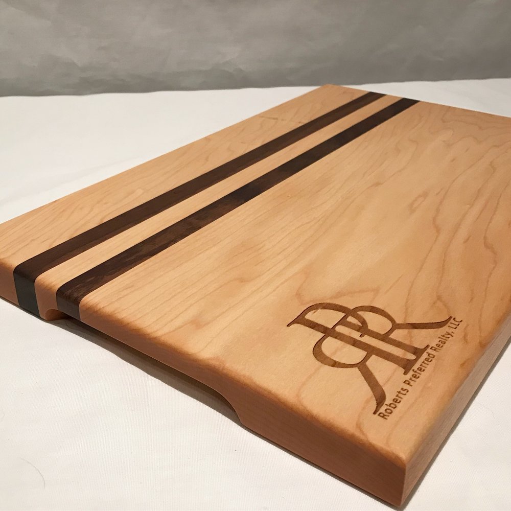 Wooden cutting board with dark stripes and engraved logo on a white background