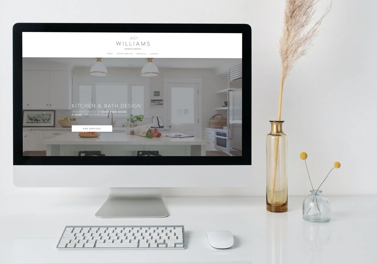 Julie Williams website on imac on white desk with dried flowers