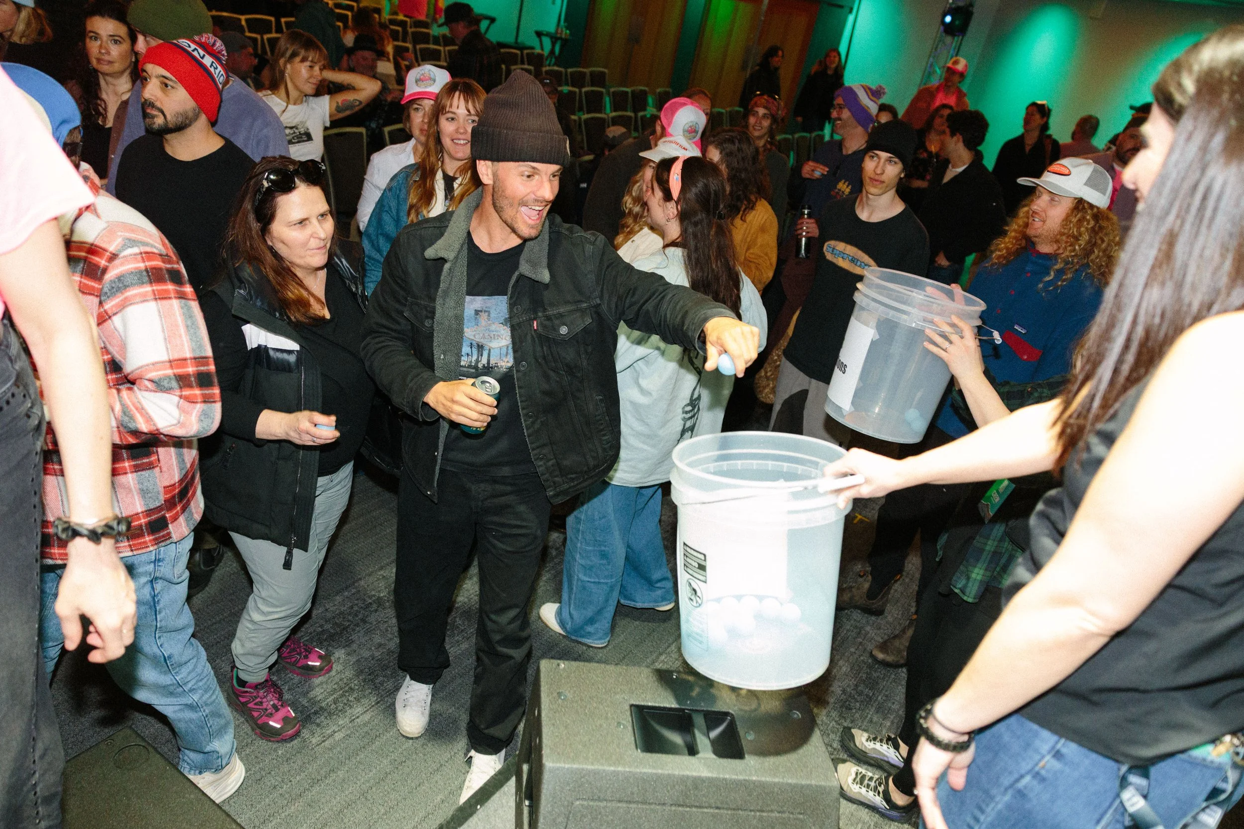 A group of people gathered around a person testing their blood alcohol content with a breathalyzer, with some holding buckets for testing.