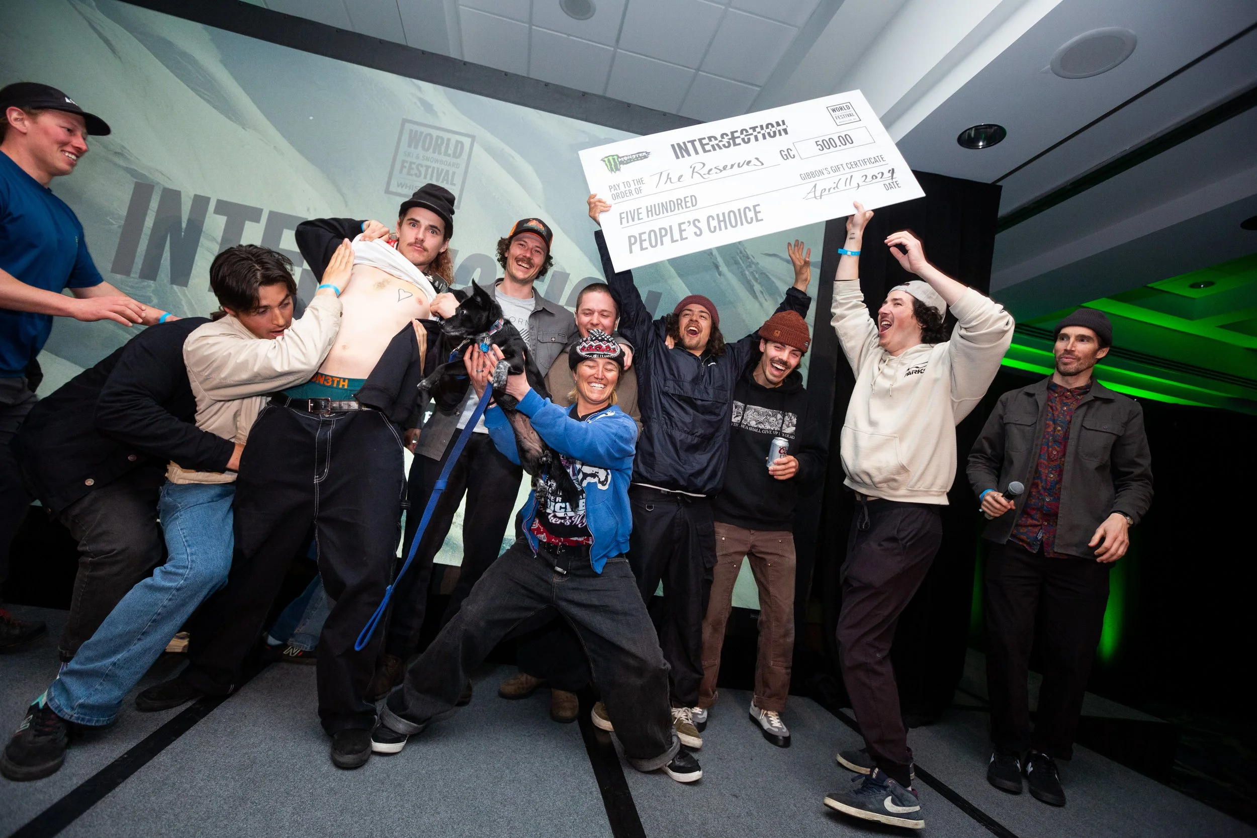 A group of people celebrating on stage with some holding a giant check for $500, labeled 'People's Choice' at an event.