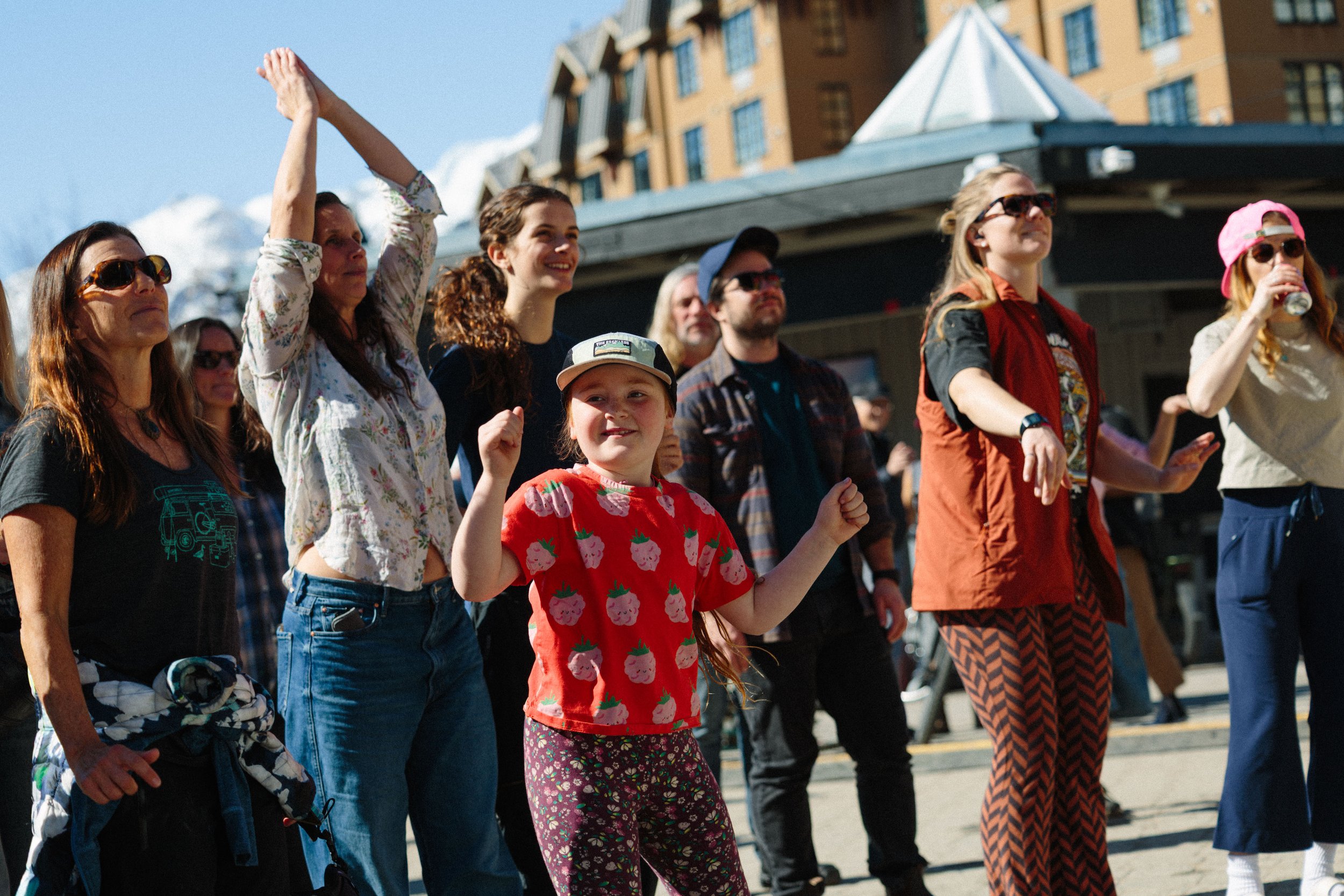 Group of diverse people standing outdoors, wearing casual clothes and sunglasses, enjoying sunny weather during daytime.