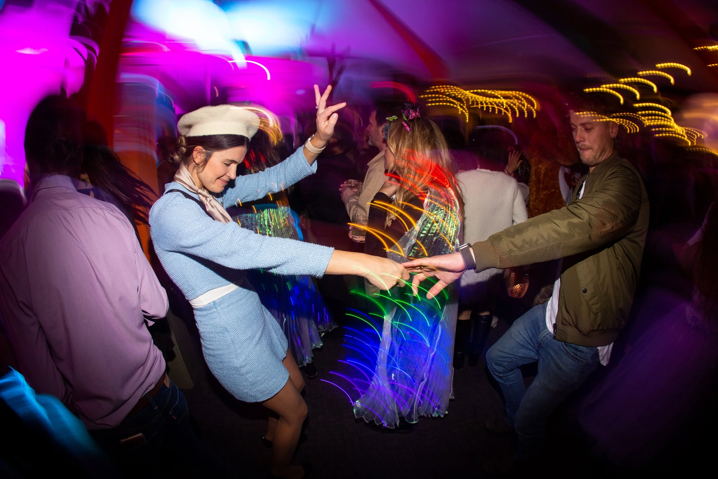 People dancing at a party with colorful lights and motion blur.