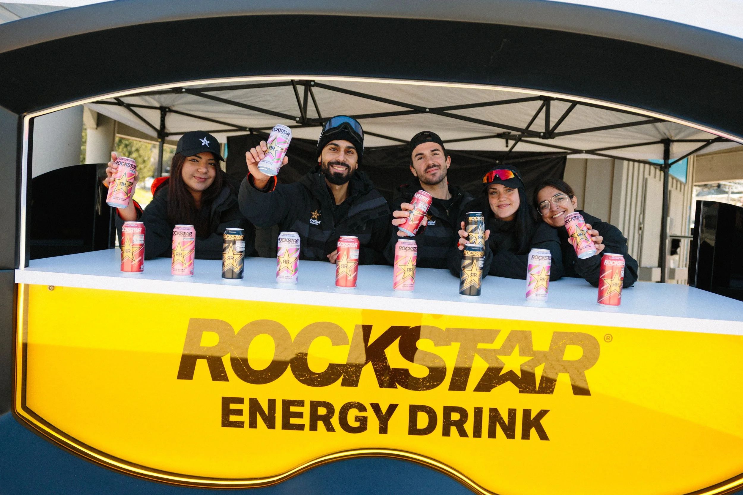 A group of five smiling people standing behind a yellow 