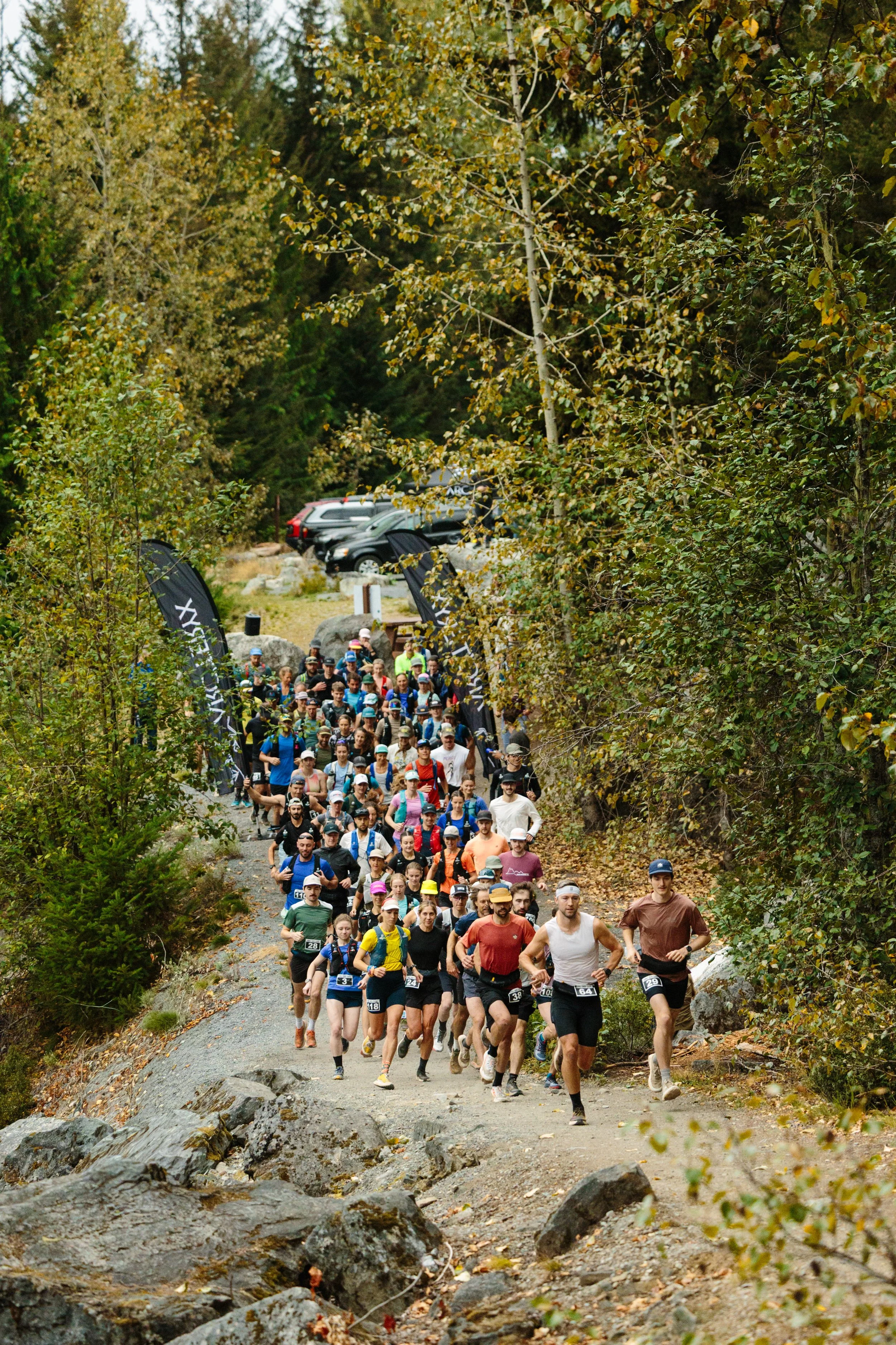 A group of runners participating in an outdoor trail race through a forested area.
