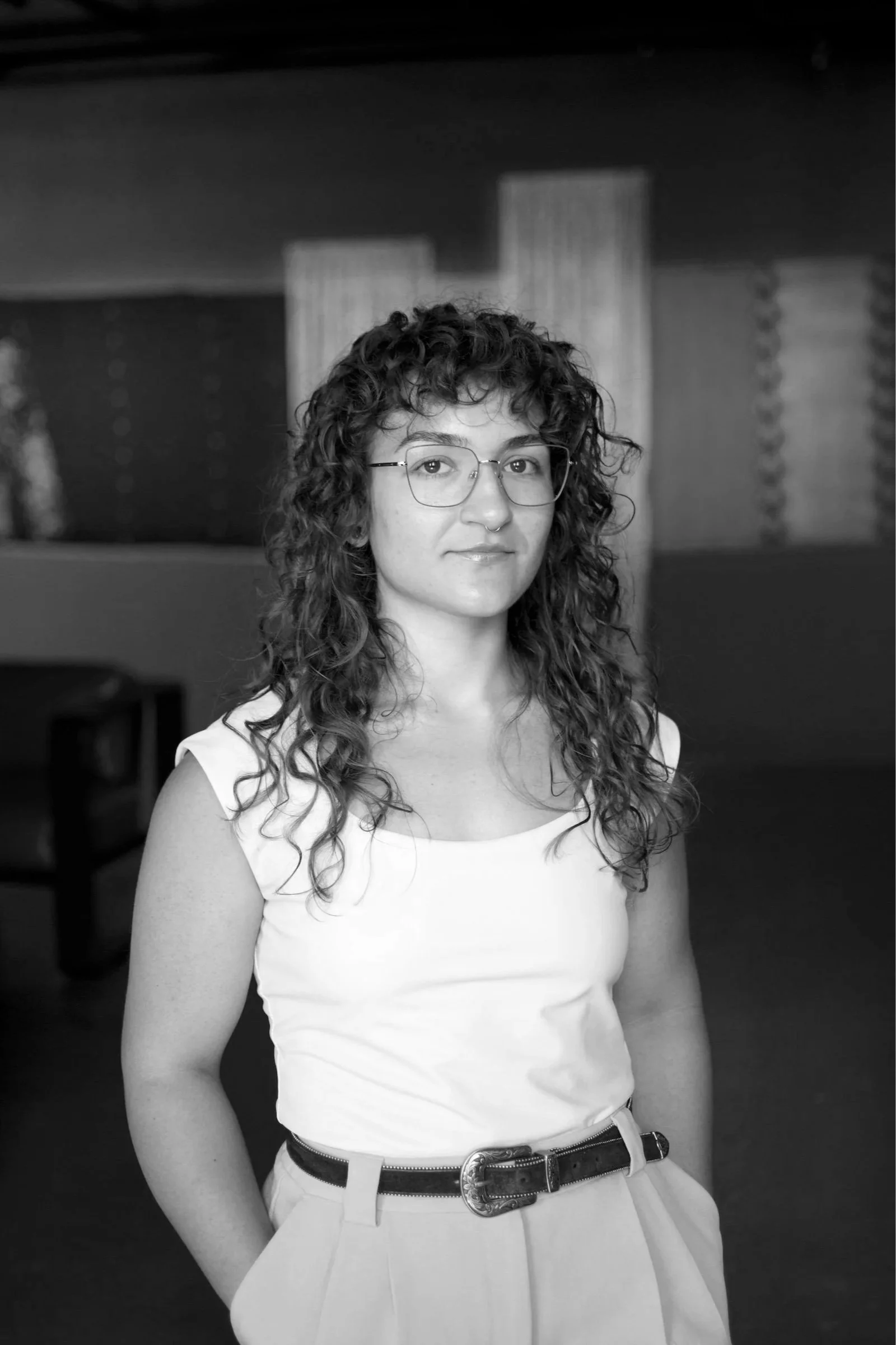 Black and white image of a young women with short wavy brown hair and brown eyes wearing a blazer and necklace