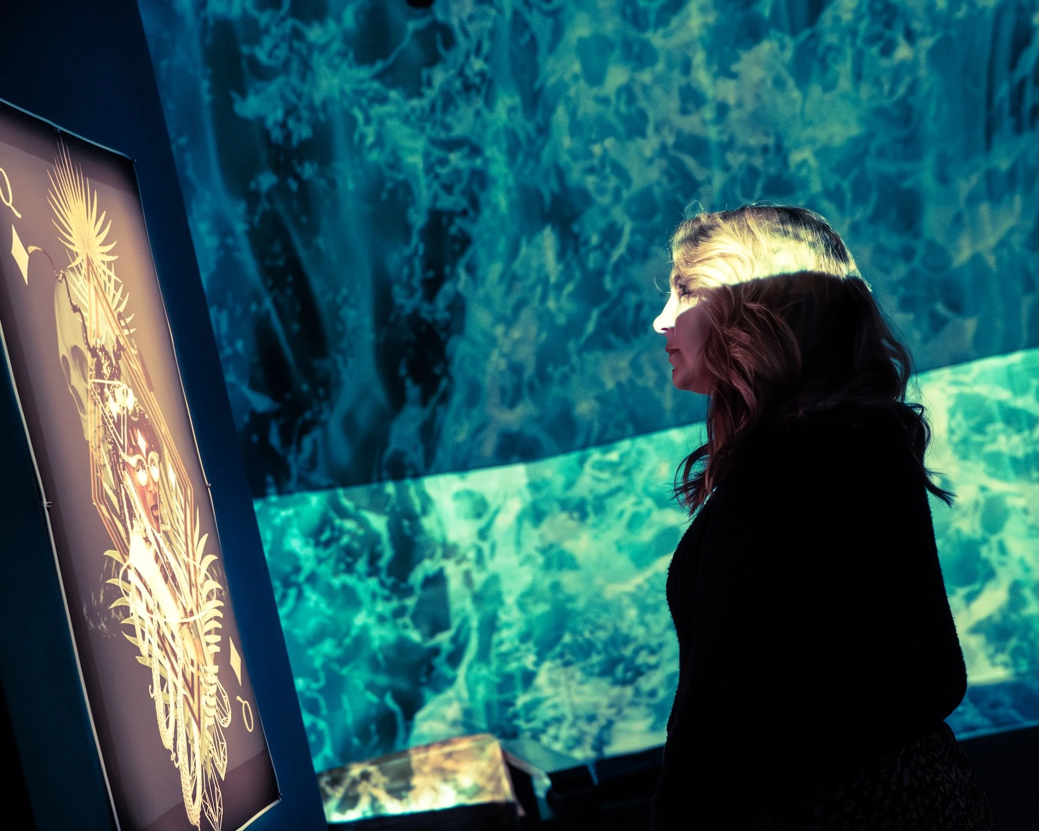 Visitor engaging with Yazz Atmore's, "Queen's Court: Queen of Diamonds," 2025, Digital Collage, 24 x 36 inches. Photo by Helen Yoseph.