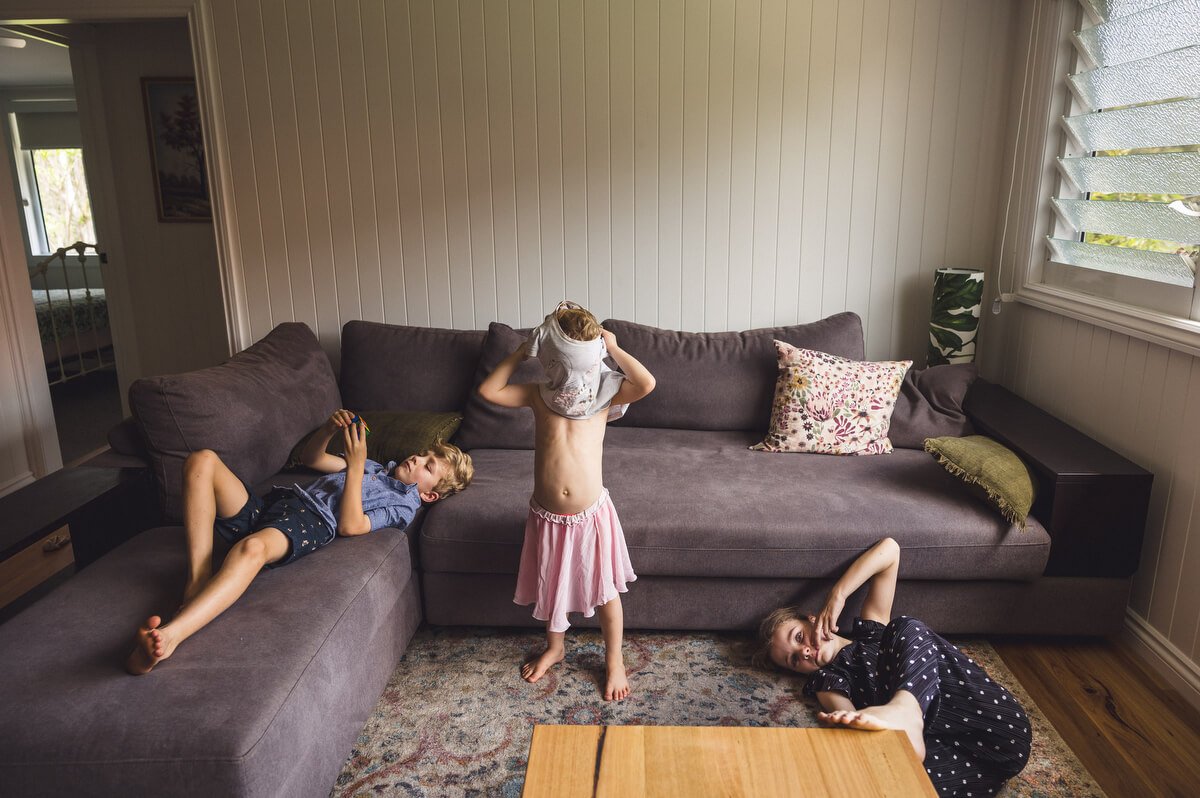 Child with shirt stuck on head while child lie beside her