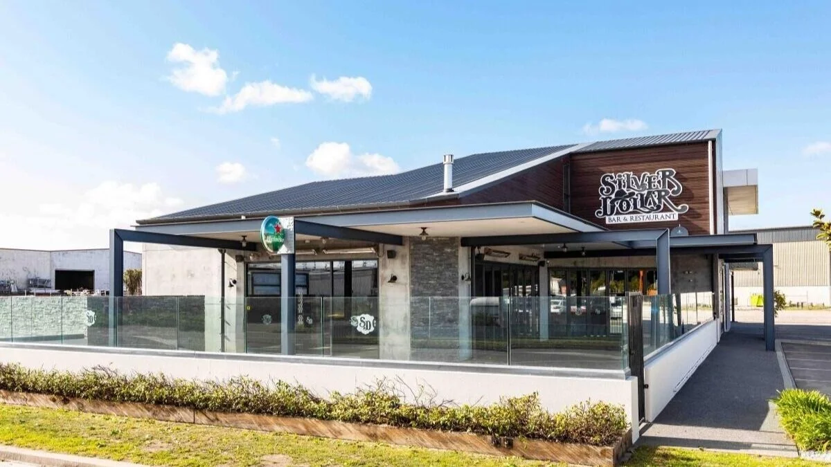 Exterior of Silver Fox Bar & Restaurant with a glass railing, Heineken sign, and a modern building design under a partly cloudy sky.