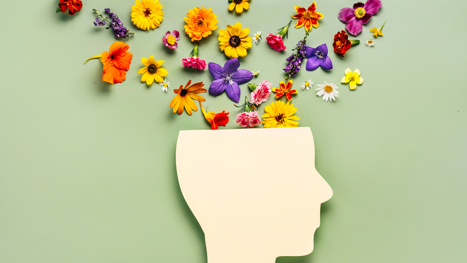 Papier-Silhouette eines menschlichen Kopfes mit einer Ansammlung bunter Blumen, die die Denkprozesse symbolisieren.