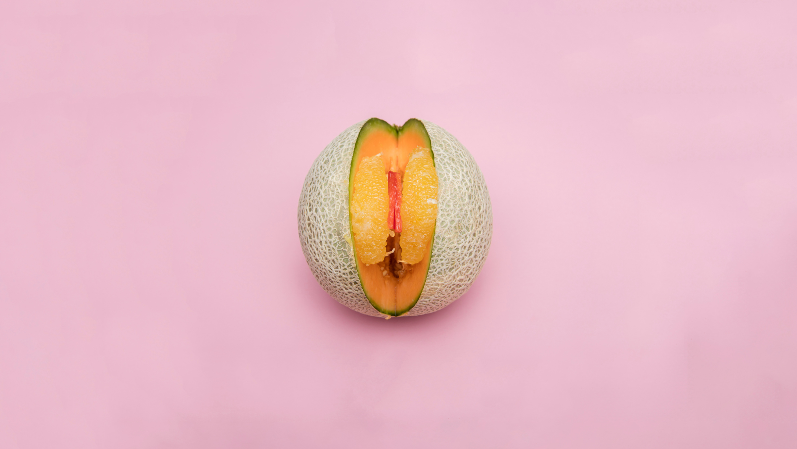 Hälfte einer Melone mit Cutout, das auf einem rosa Hintergrund liegt
