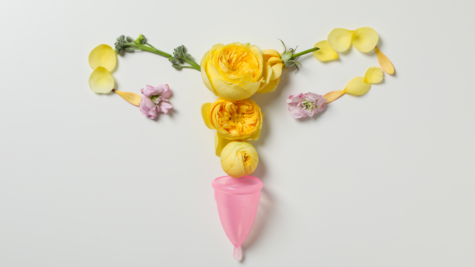Blumen und ein rosafarbenes Glas in Form eines weiblichen Fortpflanzungsorgans arrangiert, symbolisiert weibliche Fruchtbarkeit.