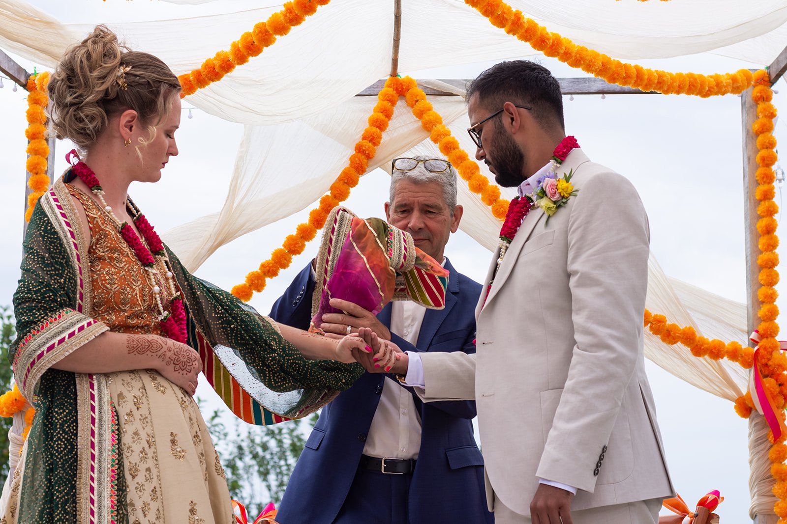 homme entoure mains du couple de mariés avec une étole.jpg