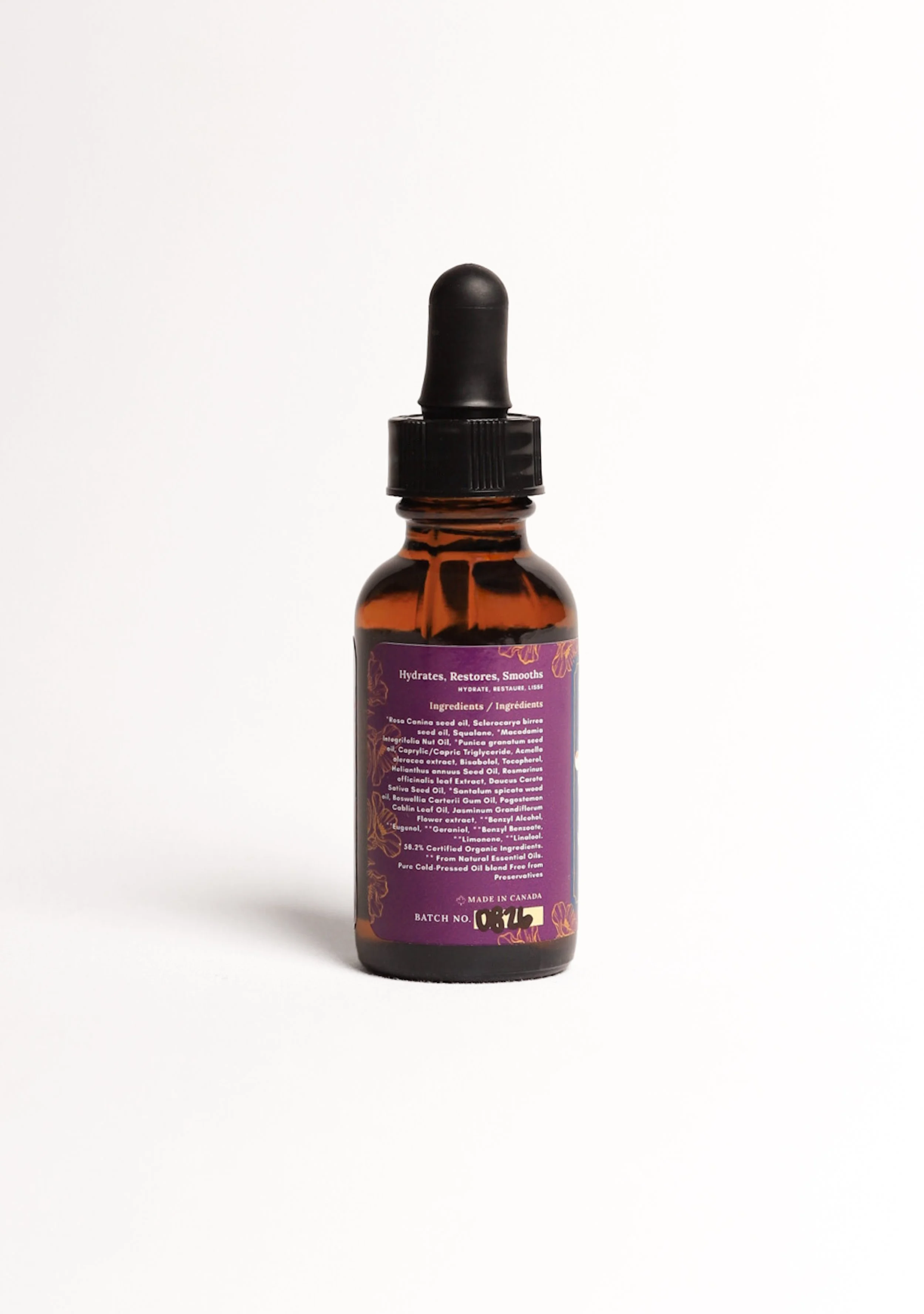 A small amber glass bottle with a black dropper cap and a purple label that lists natural ingredients and claims to hydrate, restore, and smooth skin.