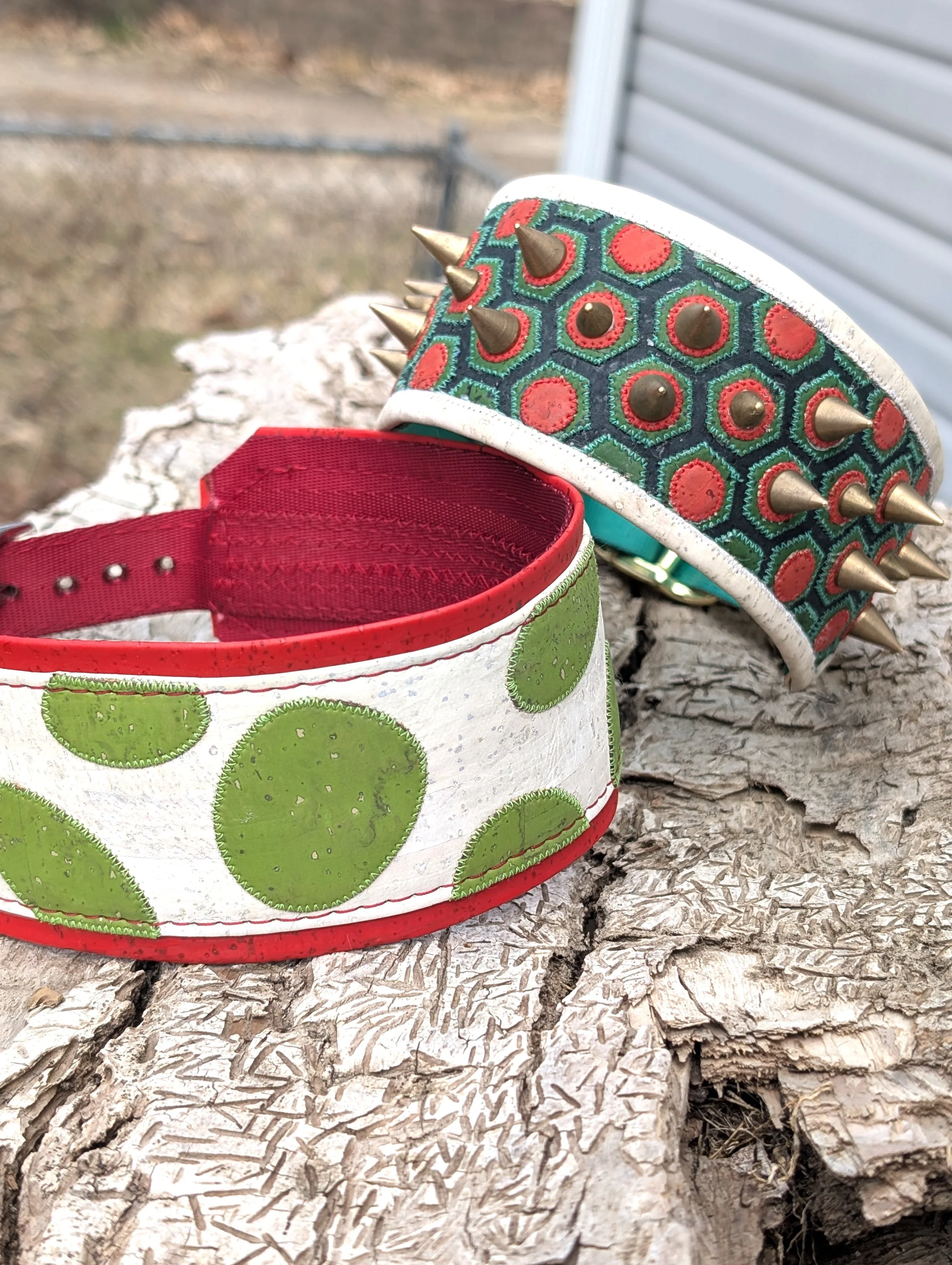 Two Mario Party themed dog collars sitting on a piece of tree bark. One is inspired by Yoshi's egg and the other by Bowser's shell.