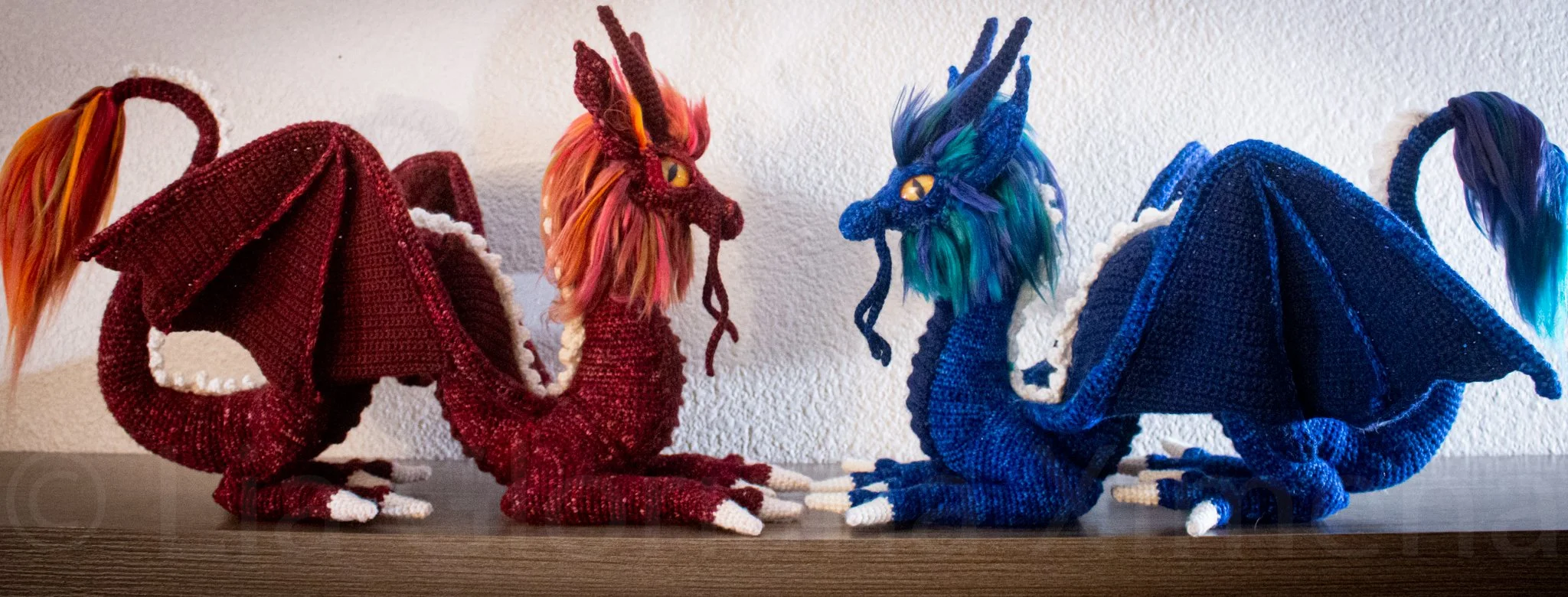 Two crocheted eastern dragons facing each other. One is re and the other is blue.