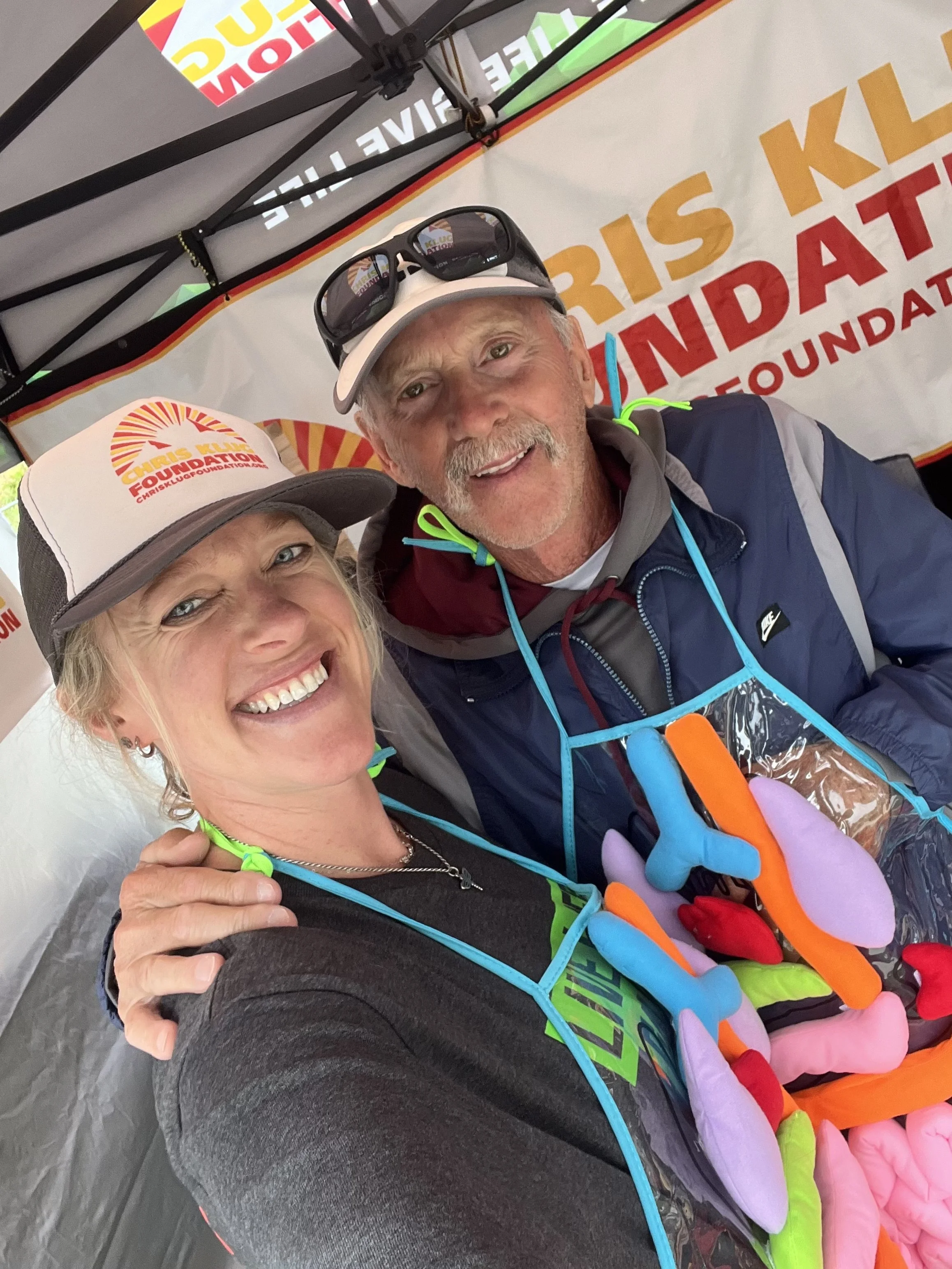 Father and daughter smiling in front of CKF banner, wearing aprons with detachable plush organs